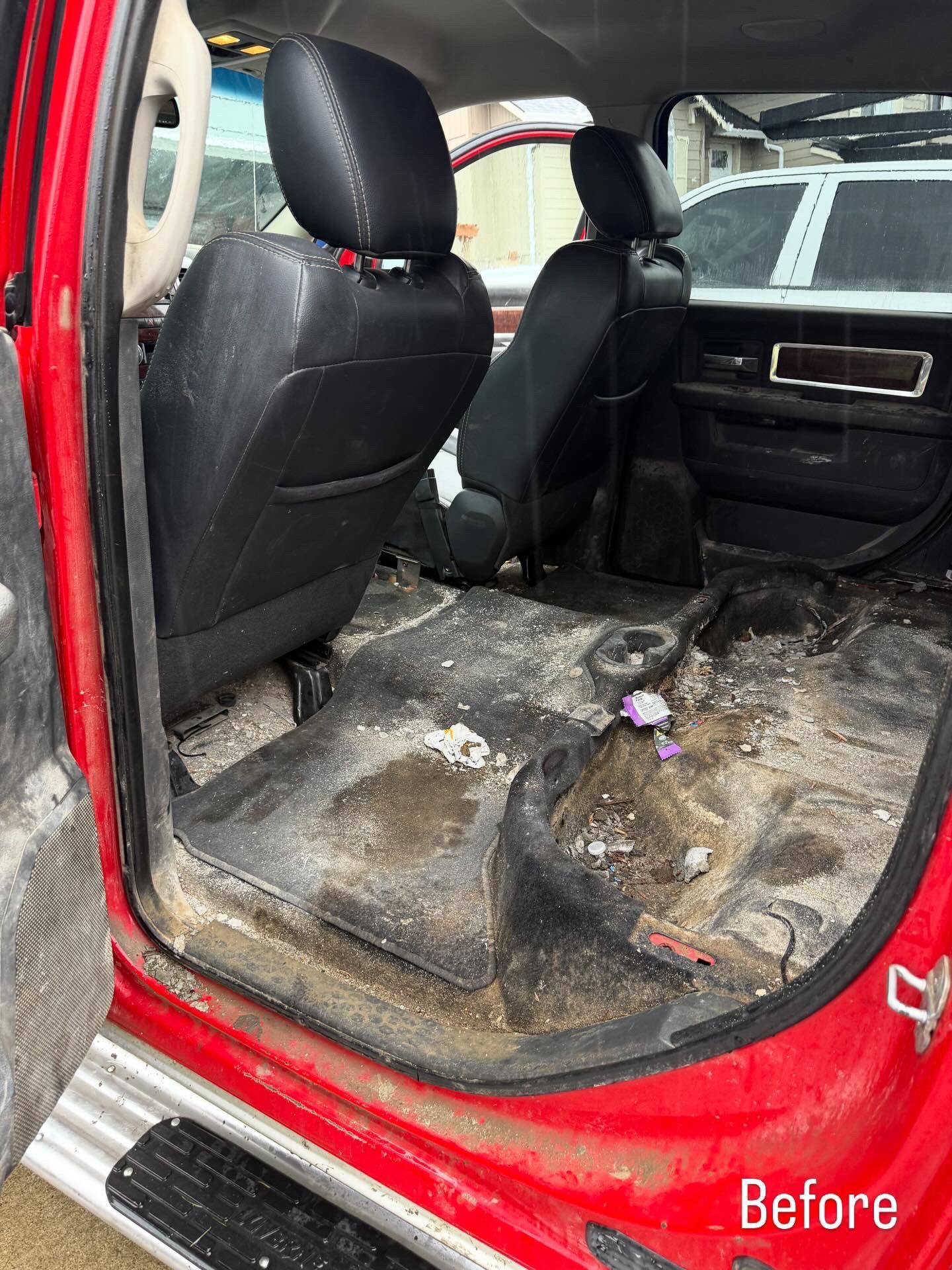 Dirty red SUV interior with removed rear seats and stained floor, “Before” text in corner