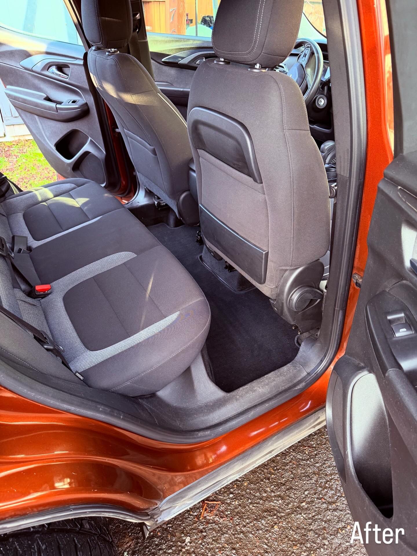 Rear car seat area with black seats and orange door frame, showing a clean interior after detailing