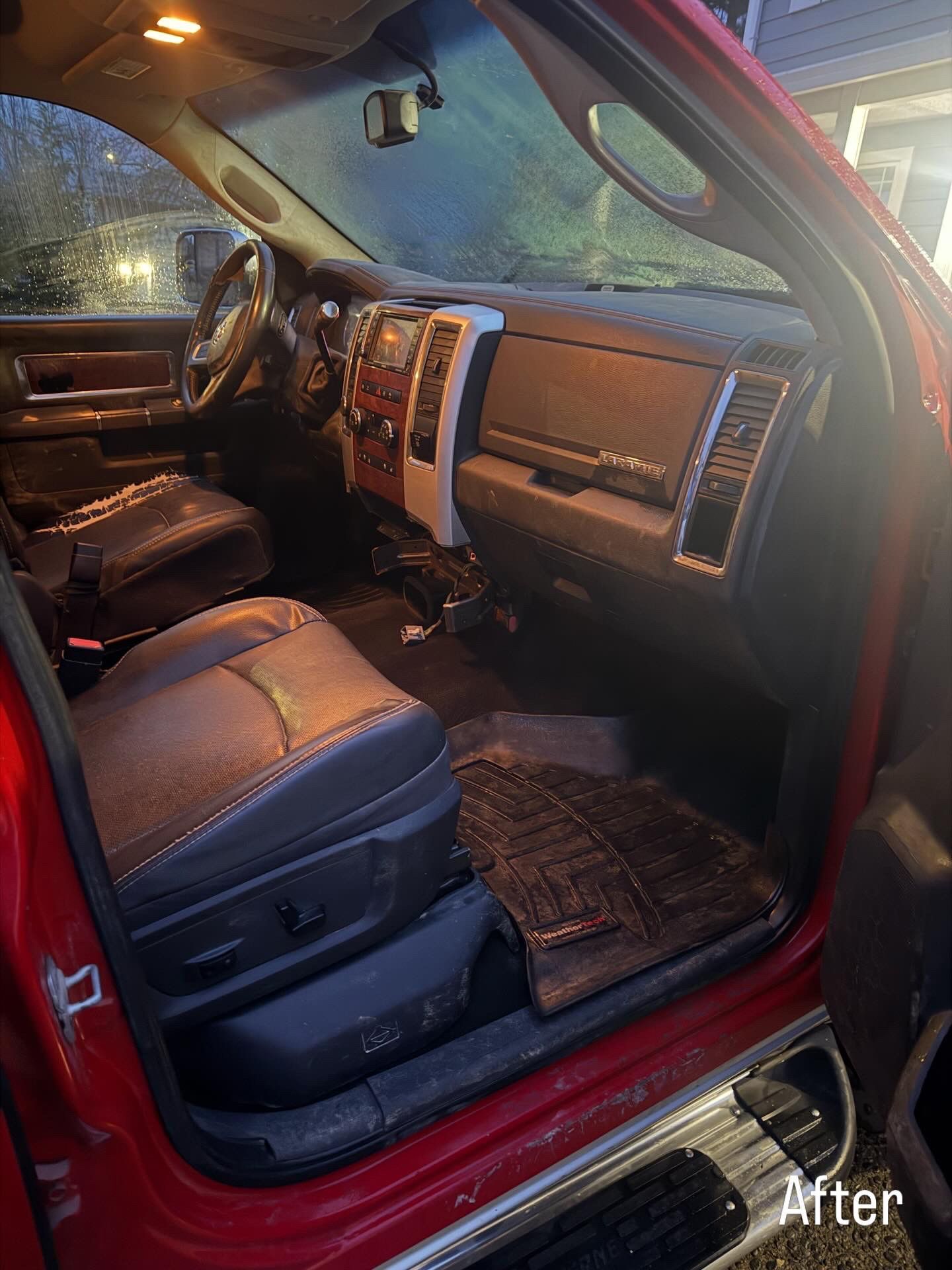 Truck interior with tan leather seats and wood-trim dashboard, viewed from the open passenger door.