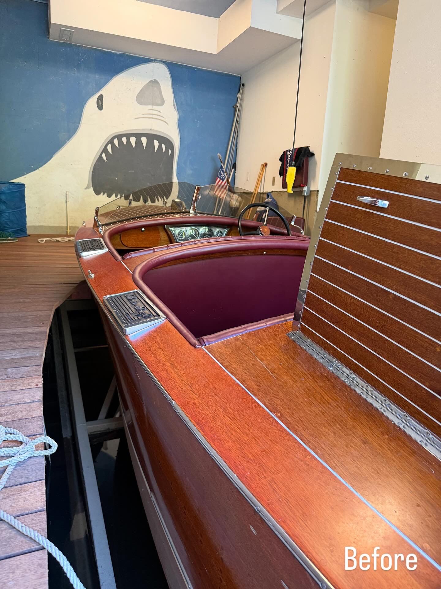 Empty indoor room with a wooden boat and a shark mural on the wall.