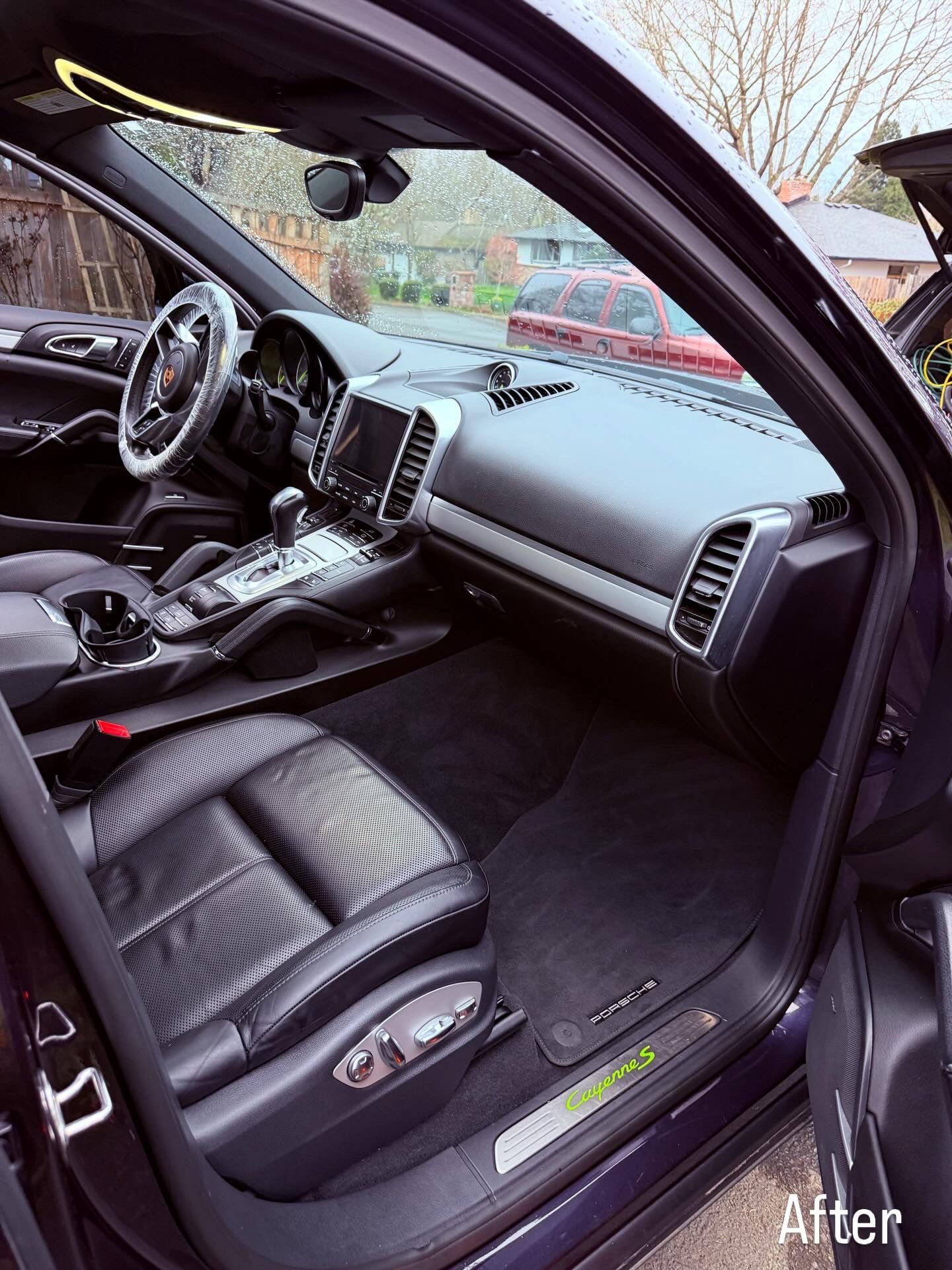 Black car interior with open driver door, showing dashboard, steering wheel, and leather seats.