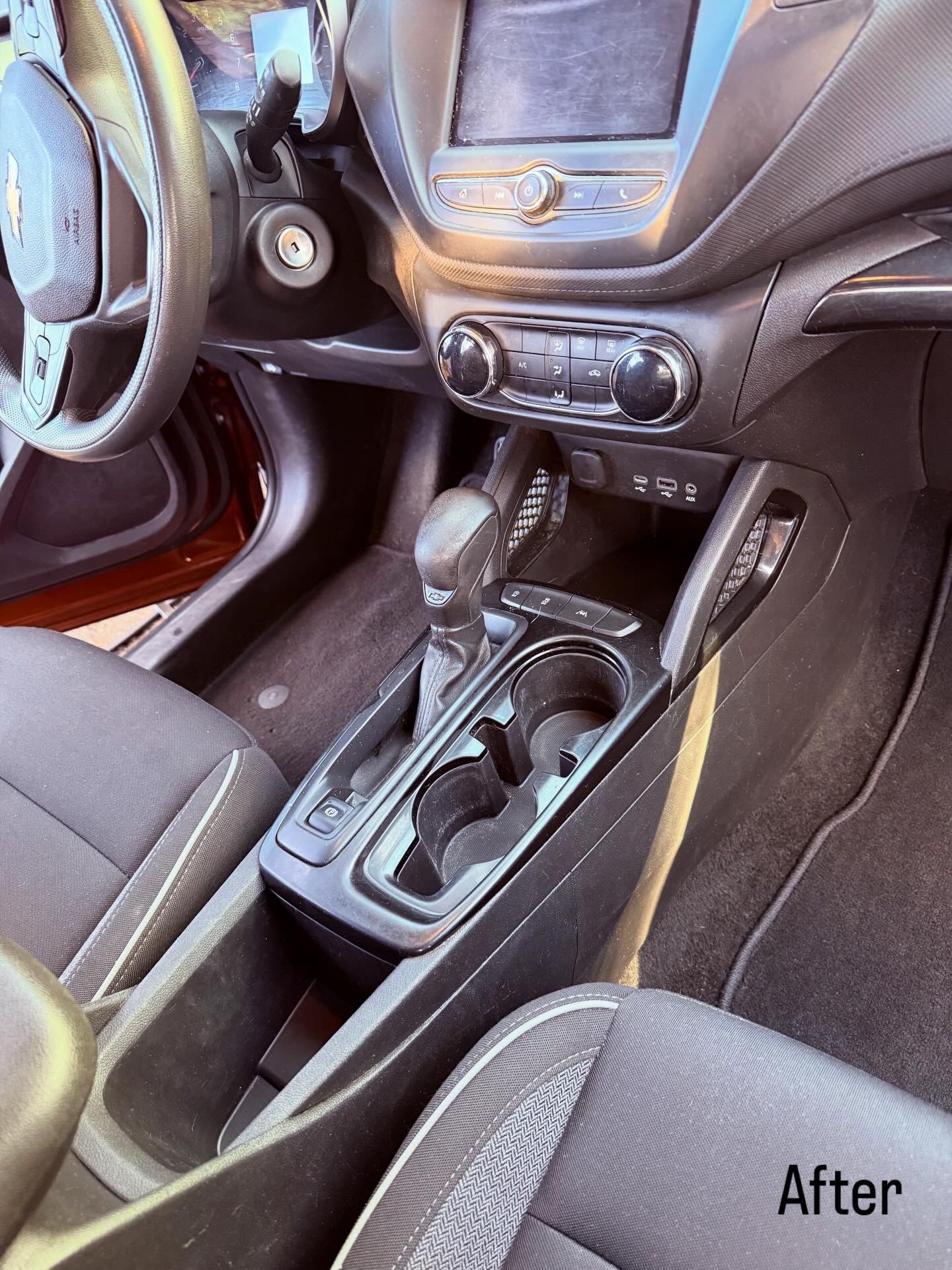 Car interior with center console and gear shift, showing a black dashboard and cloth seats.