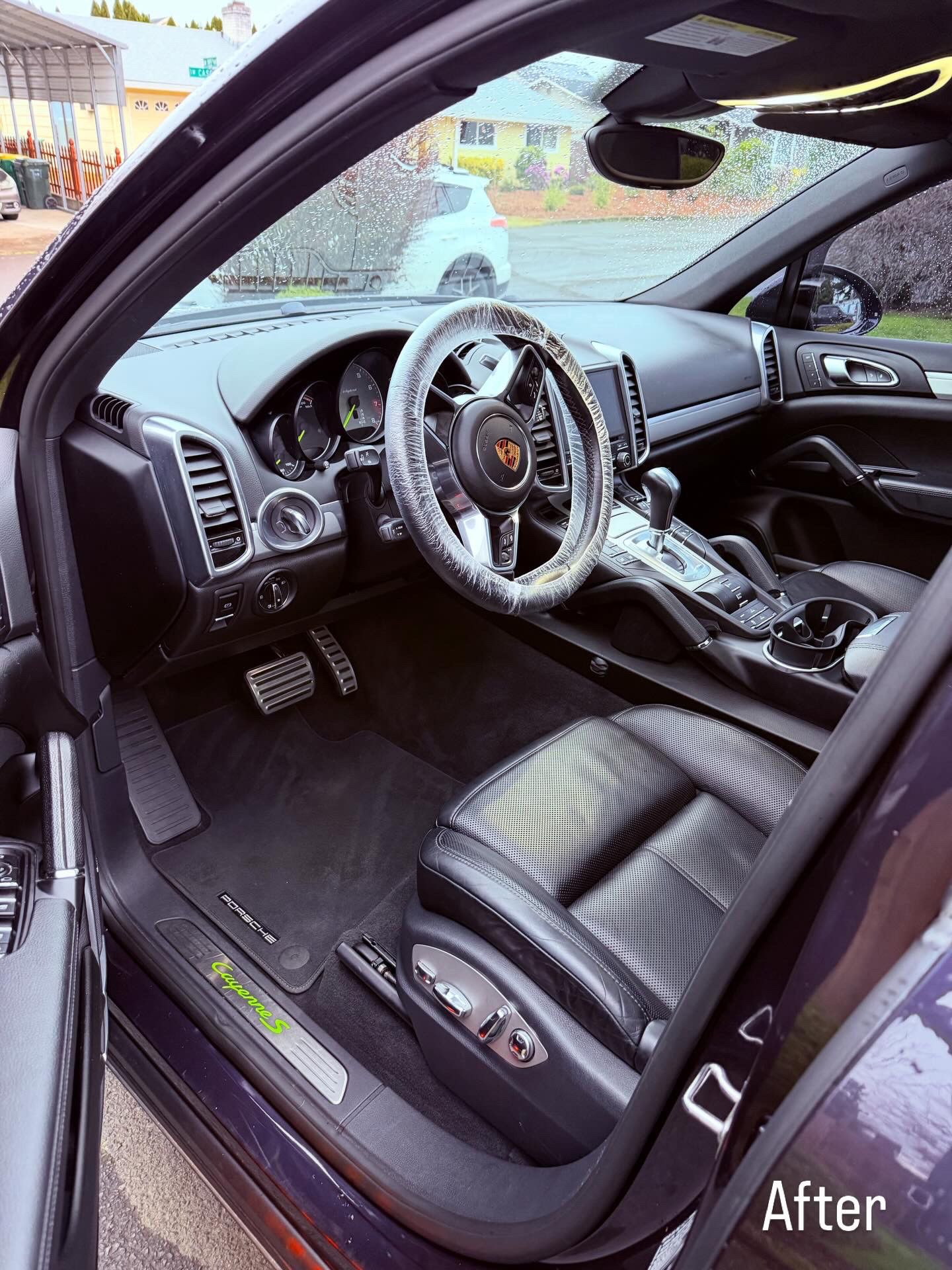 Black car interior with black leather seats and steering wheel, shown from the driver’s side door.