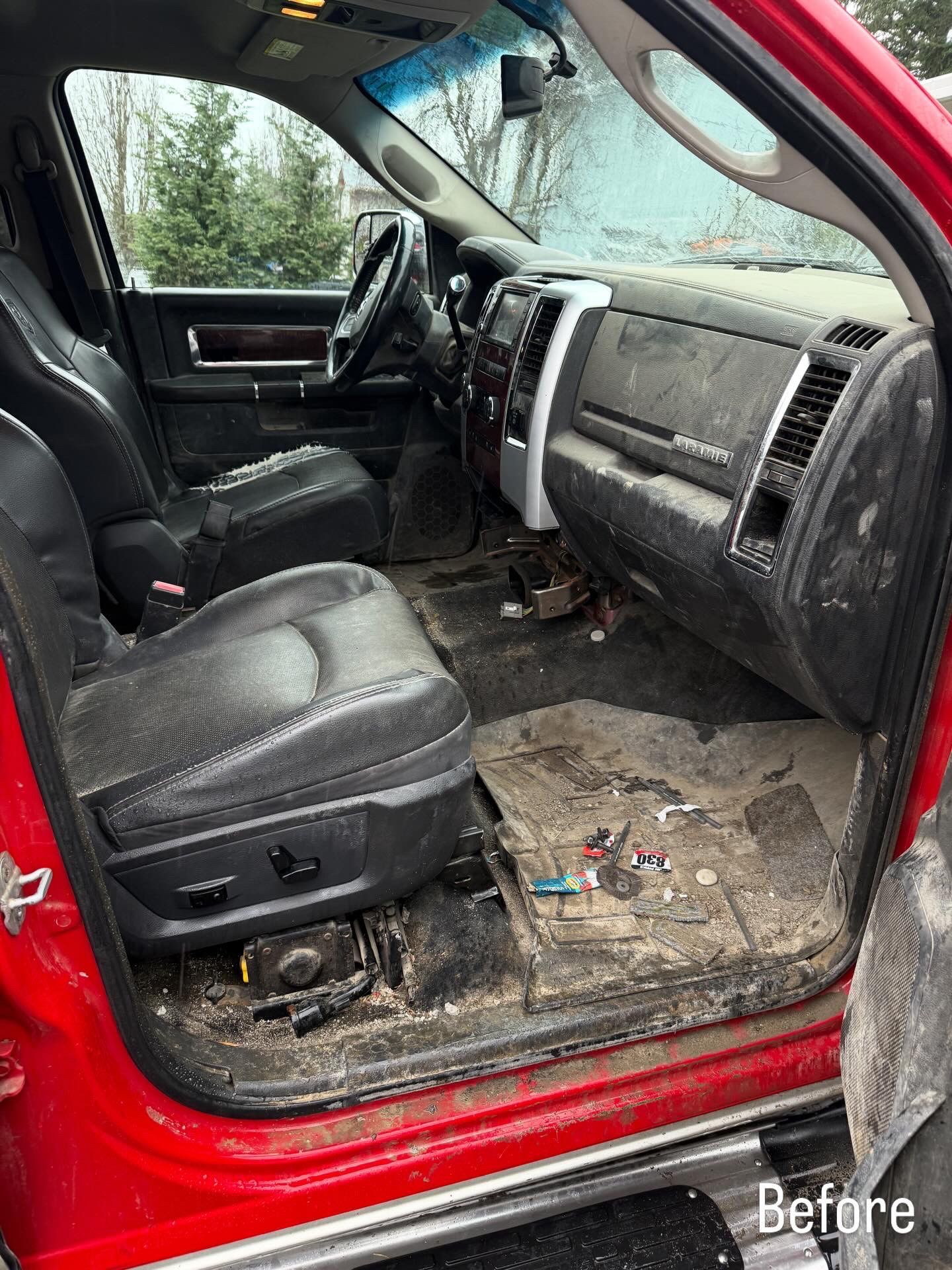 Dirty red truck interior with torn black seats and debris on the floor