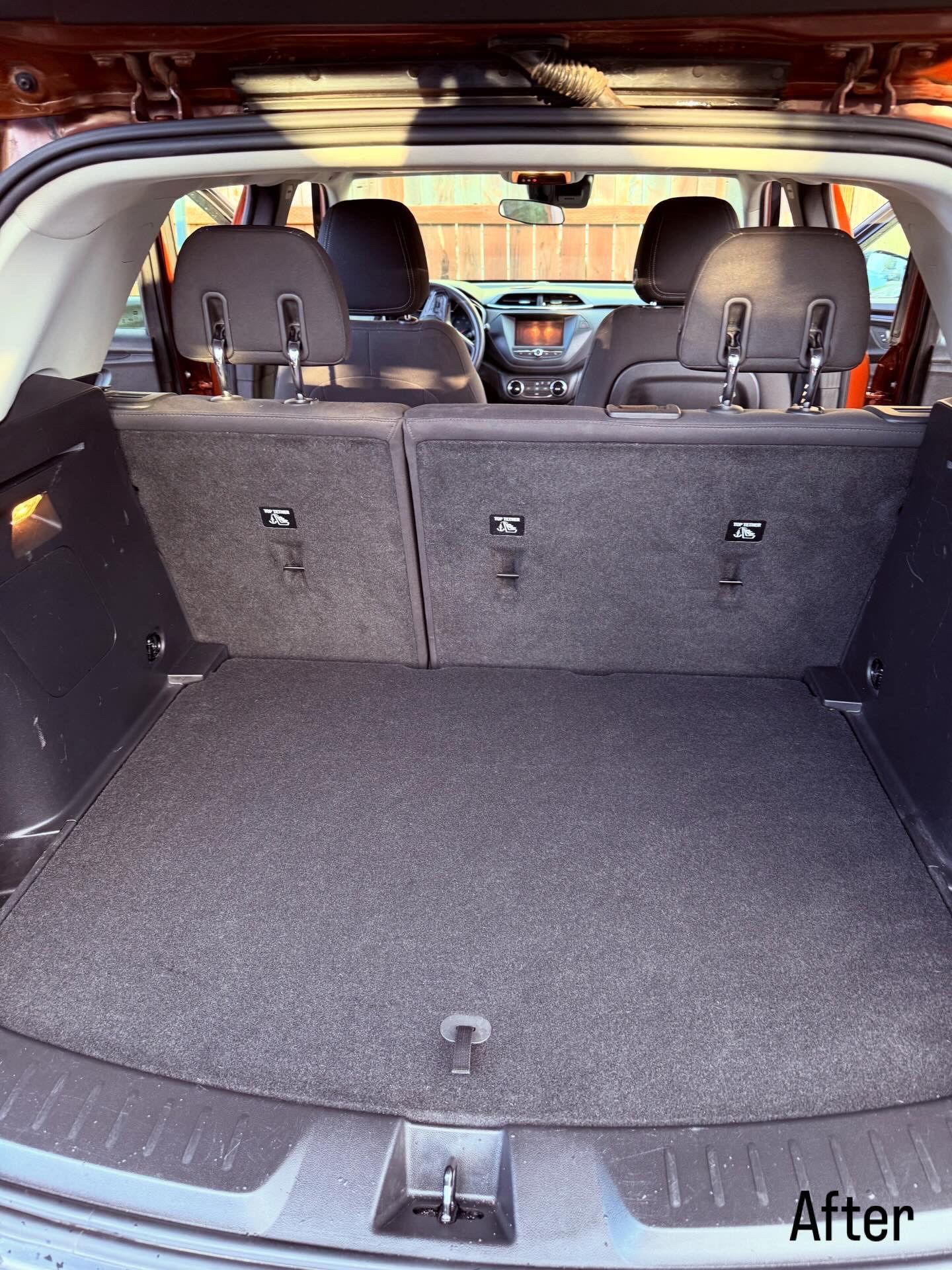 Car trunk with rear seats folded down, creating a flat gray cargo space.