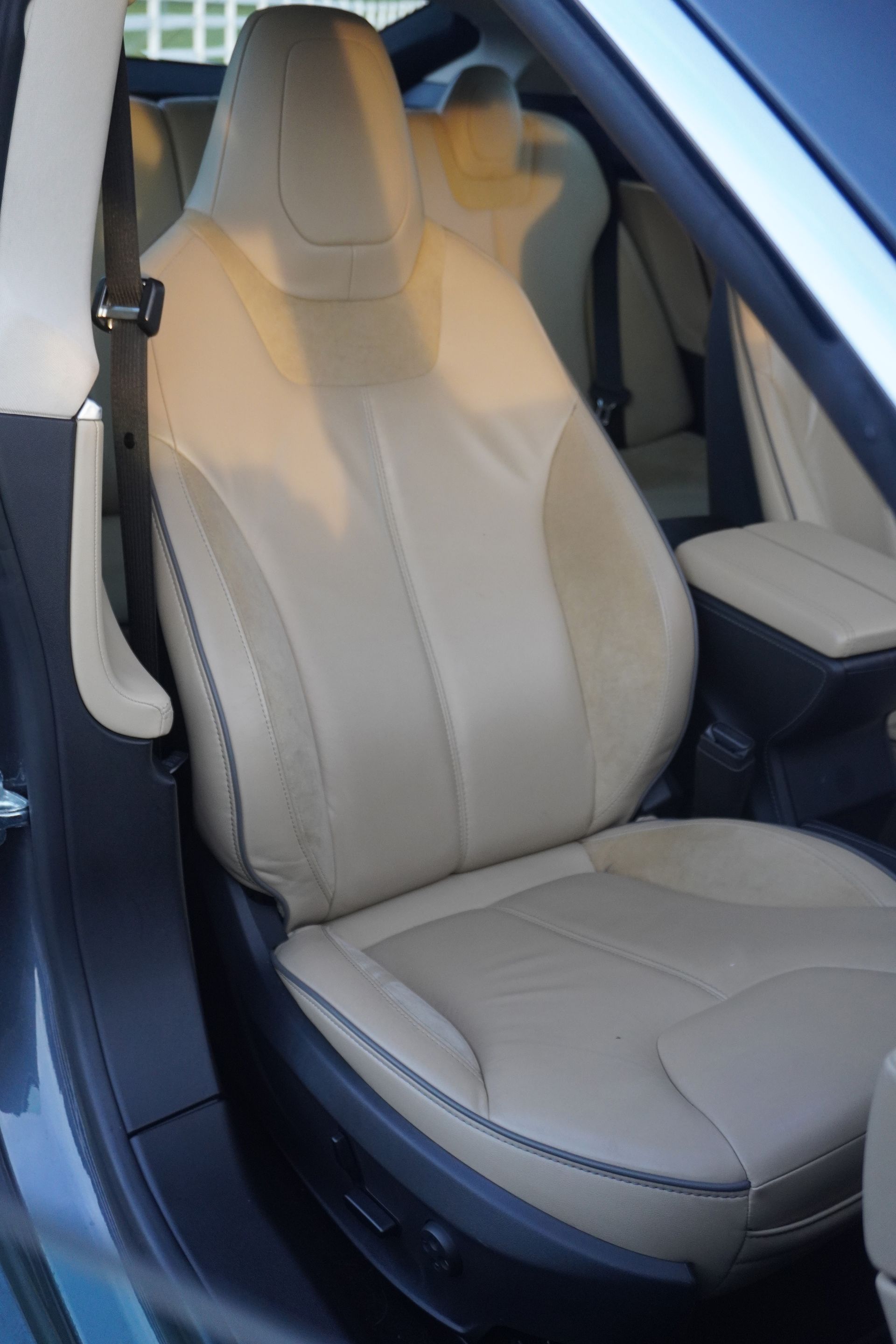 Beige leather car seat in a vehicle interior, seen from the side.