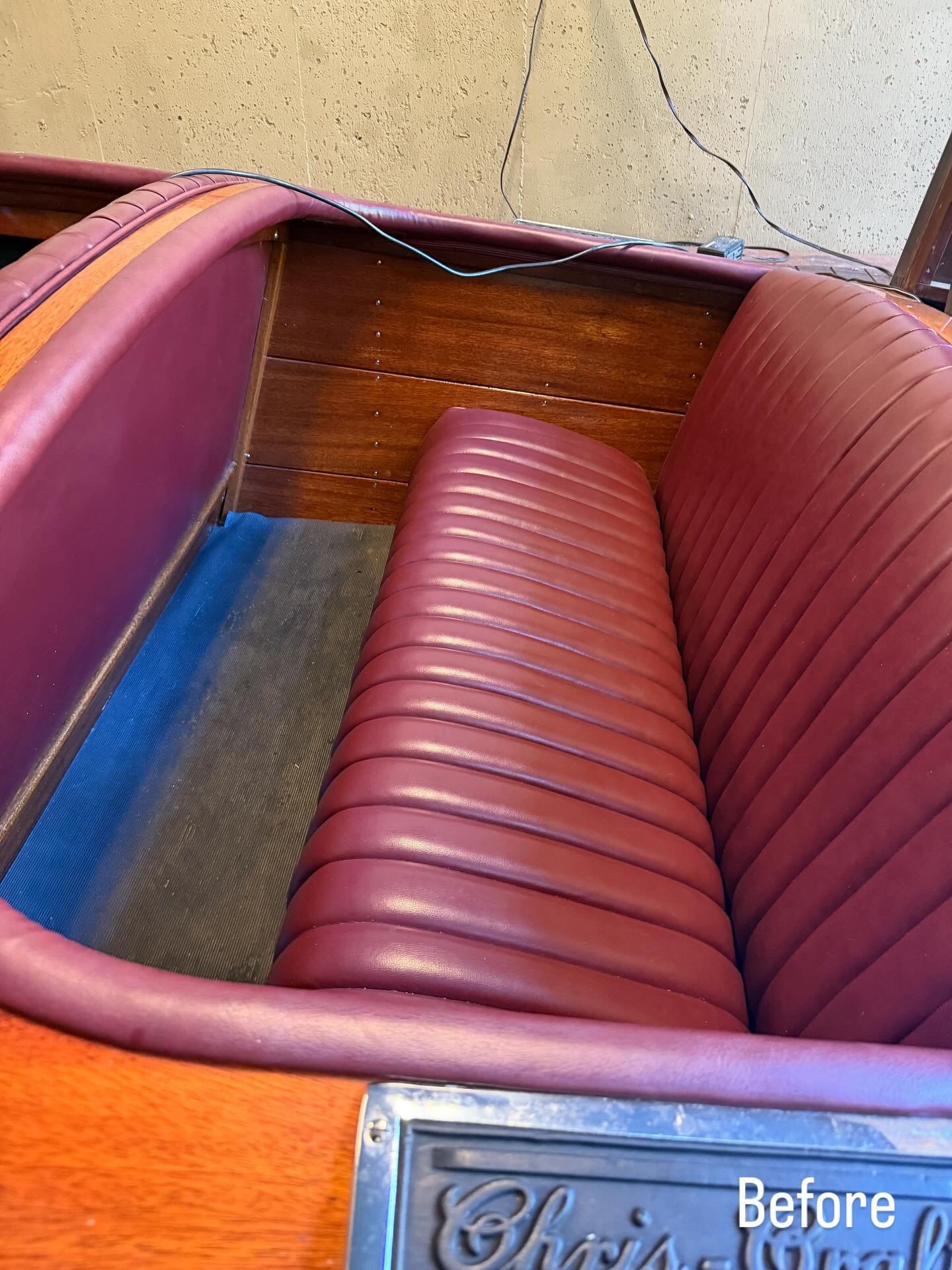 Vintage car interior with red vinyl bench seat, blue floor, and wood panel trim