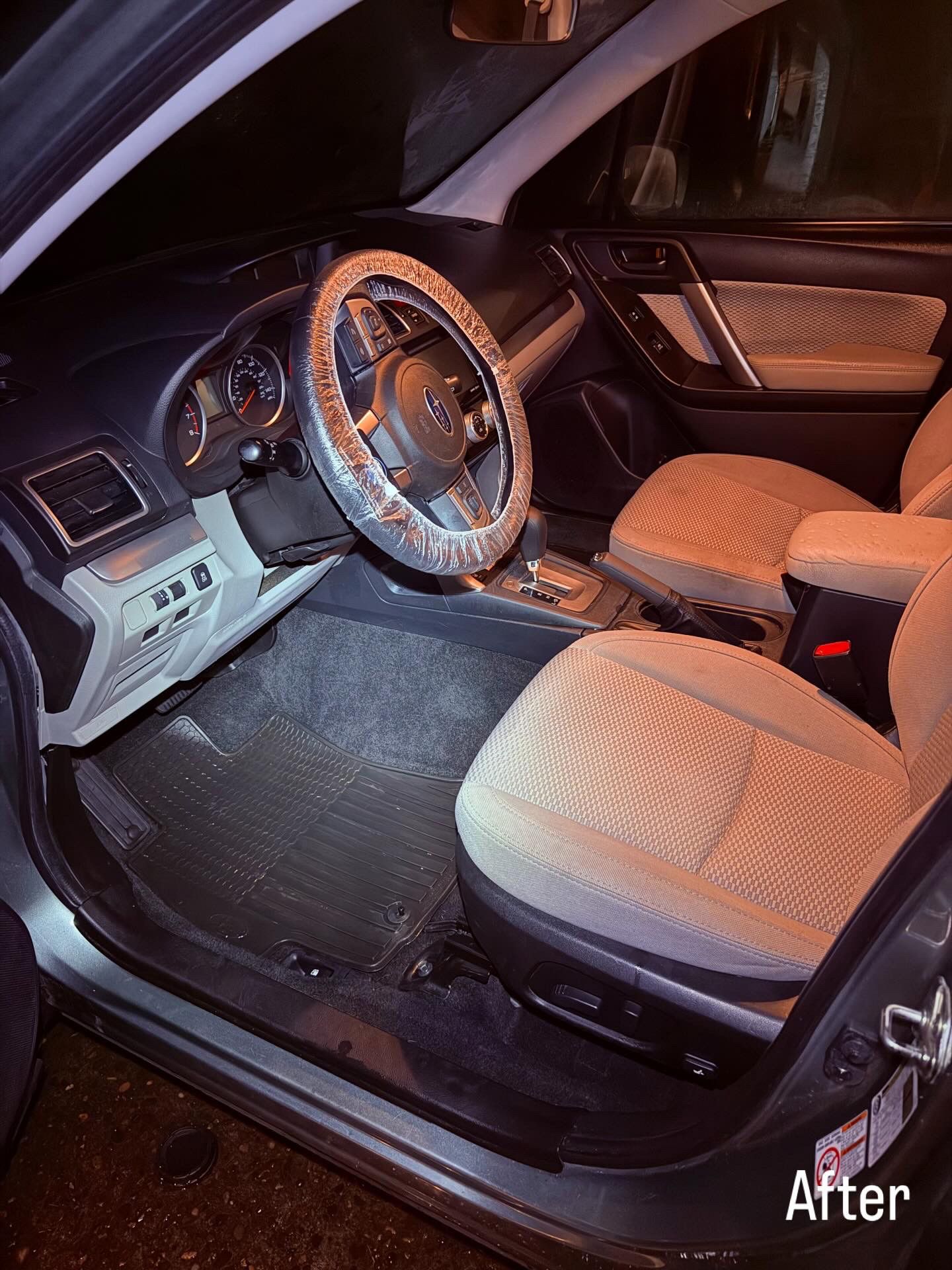 Car interior with black-and-tan seats, steering wheel cover, and illuminated dashboard at night