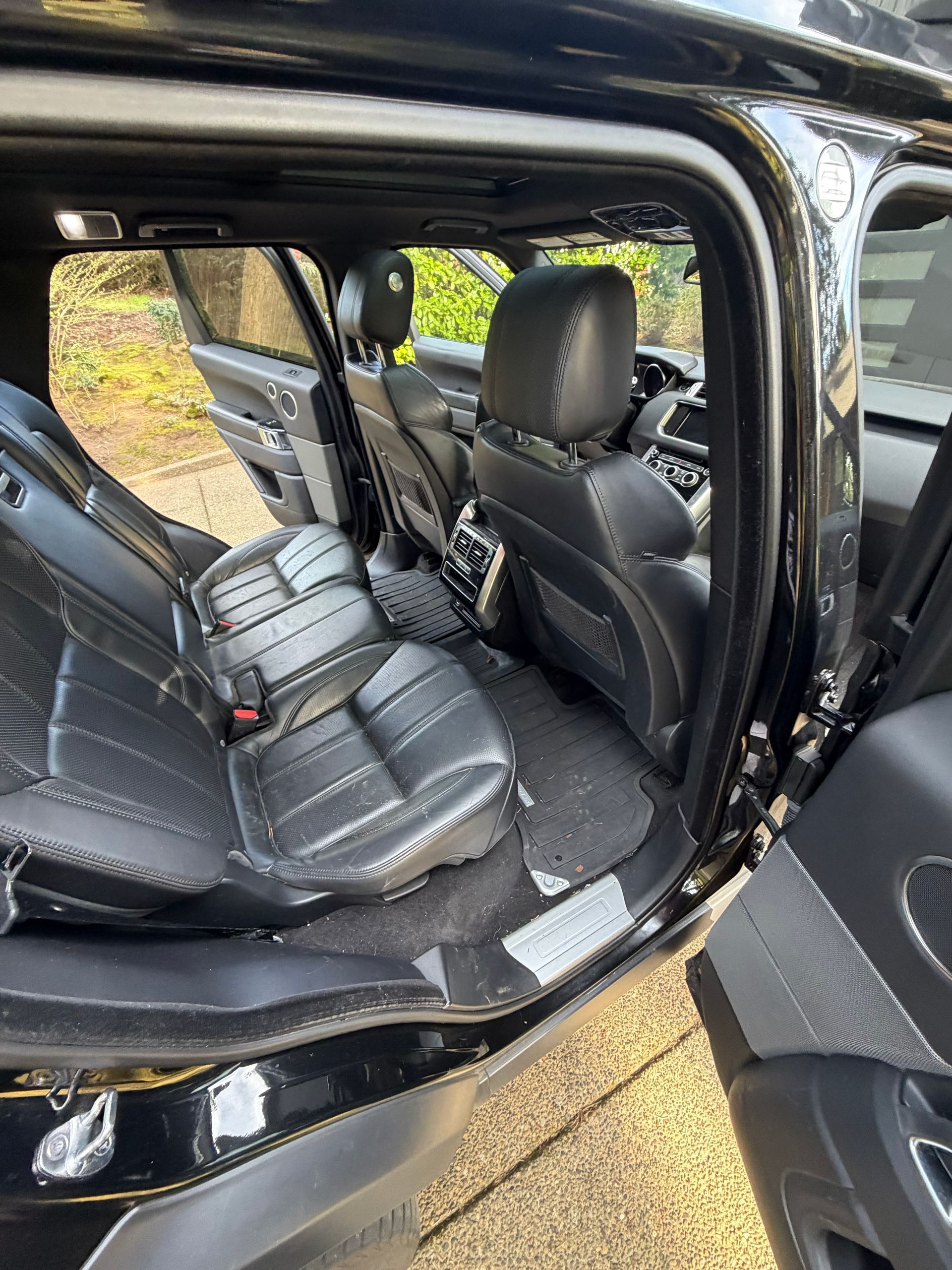Open car door showing black leather rear and front seats inside a vehicle