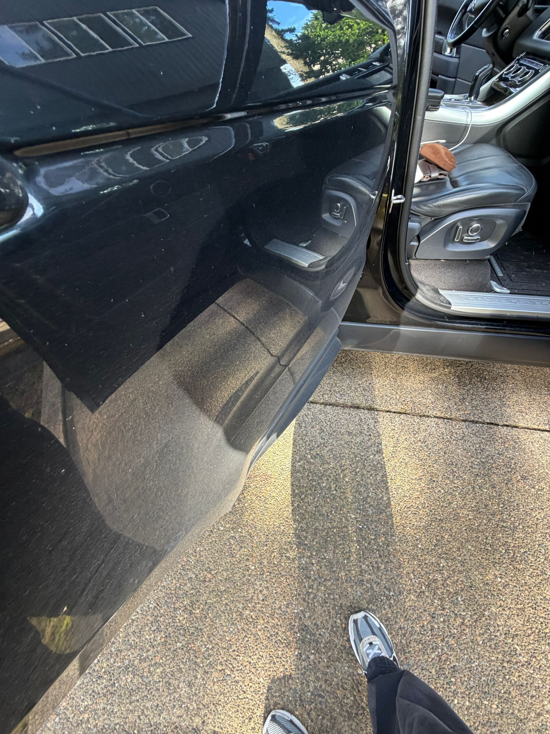 Close-up of two dark cars with a damaged side mirror and scratched door near a parking curb