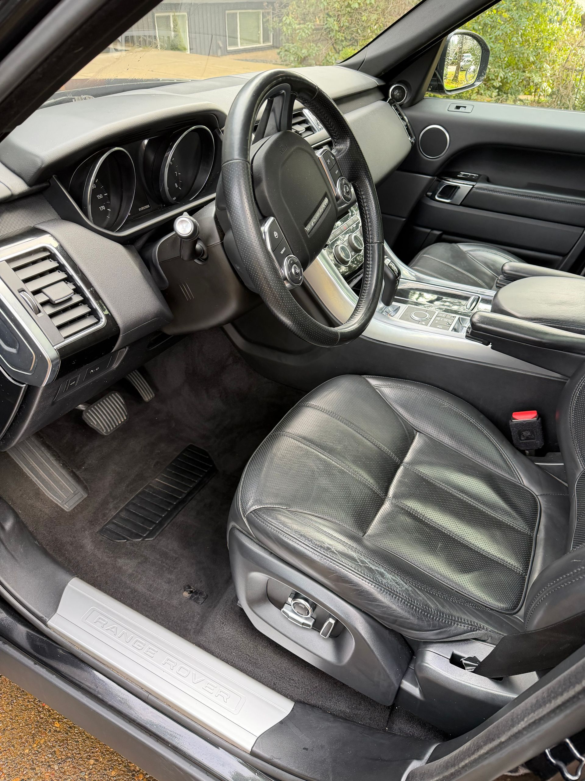 Car interior with black leather driver’s seat, steering wheel, and dashboard visible.