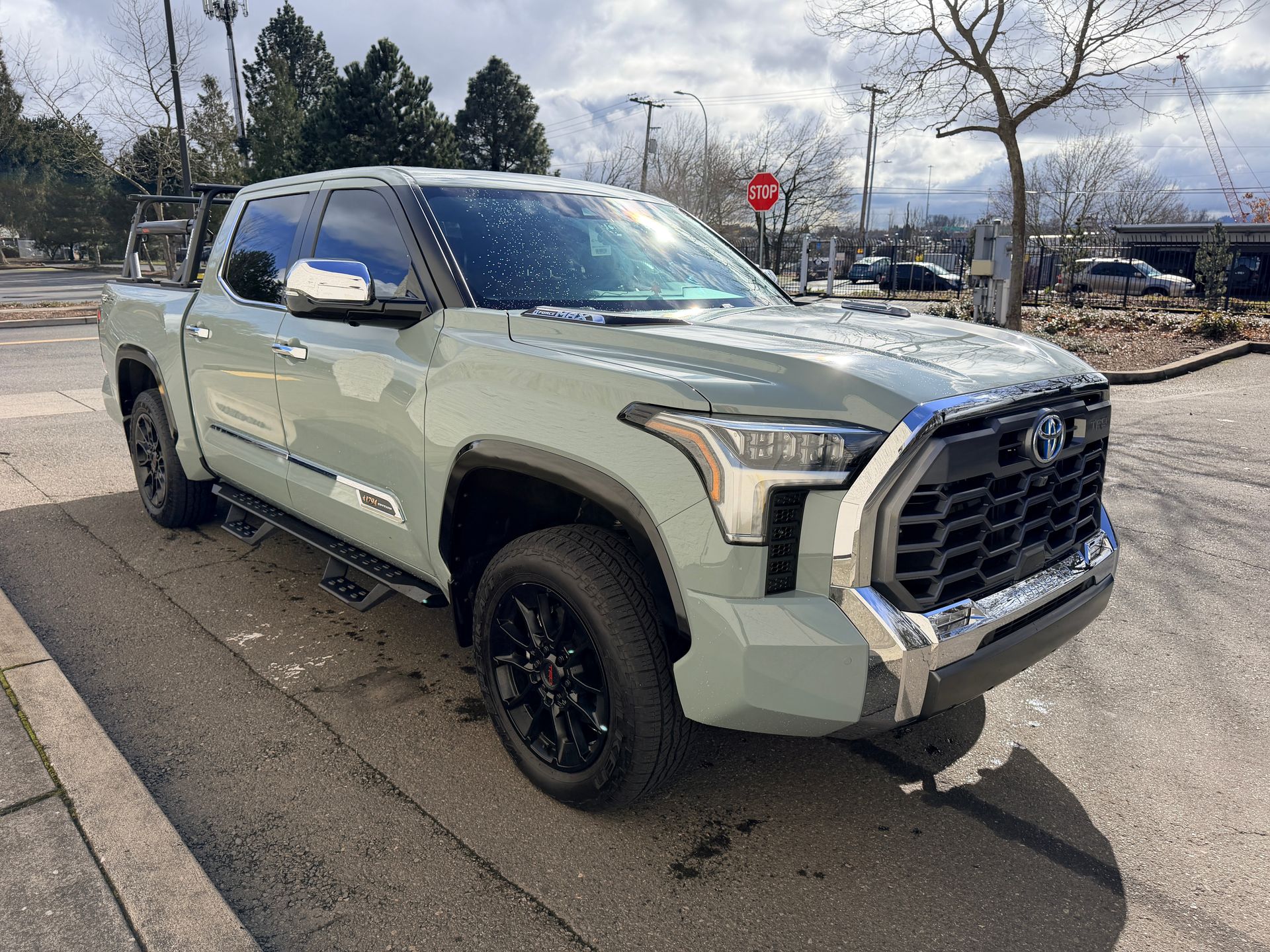 Light green pickup truck parked on a street under cloudy skies