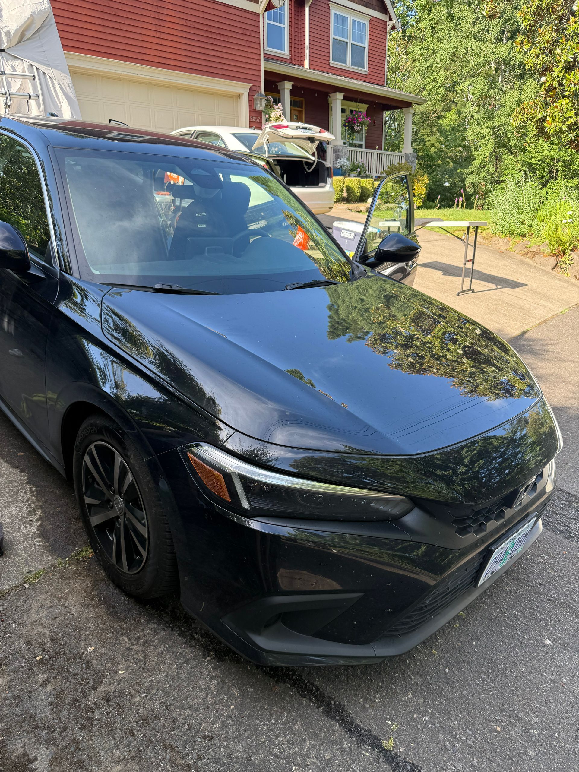 Black compact SUV parked in a driveway beside a brick house on a sunny day