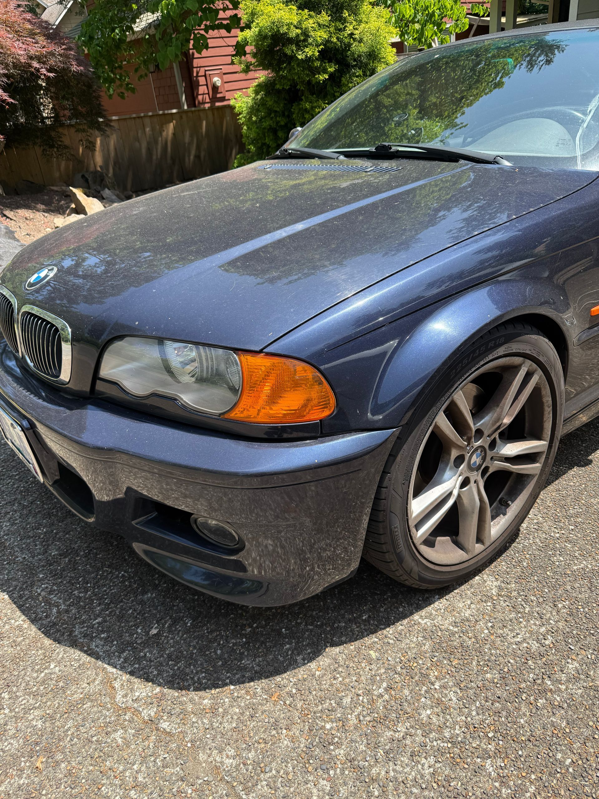 Blue BMW parked on a sunny driveway, front-left view with damaged front bumper