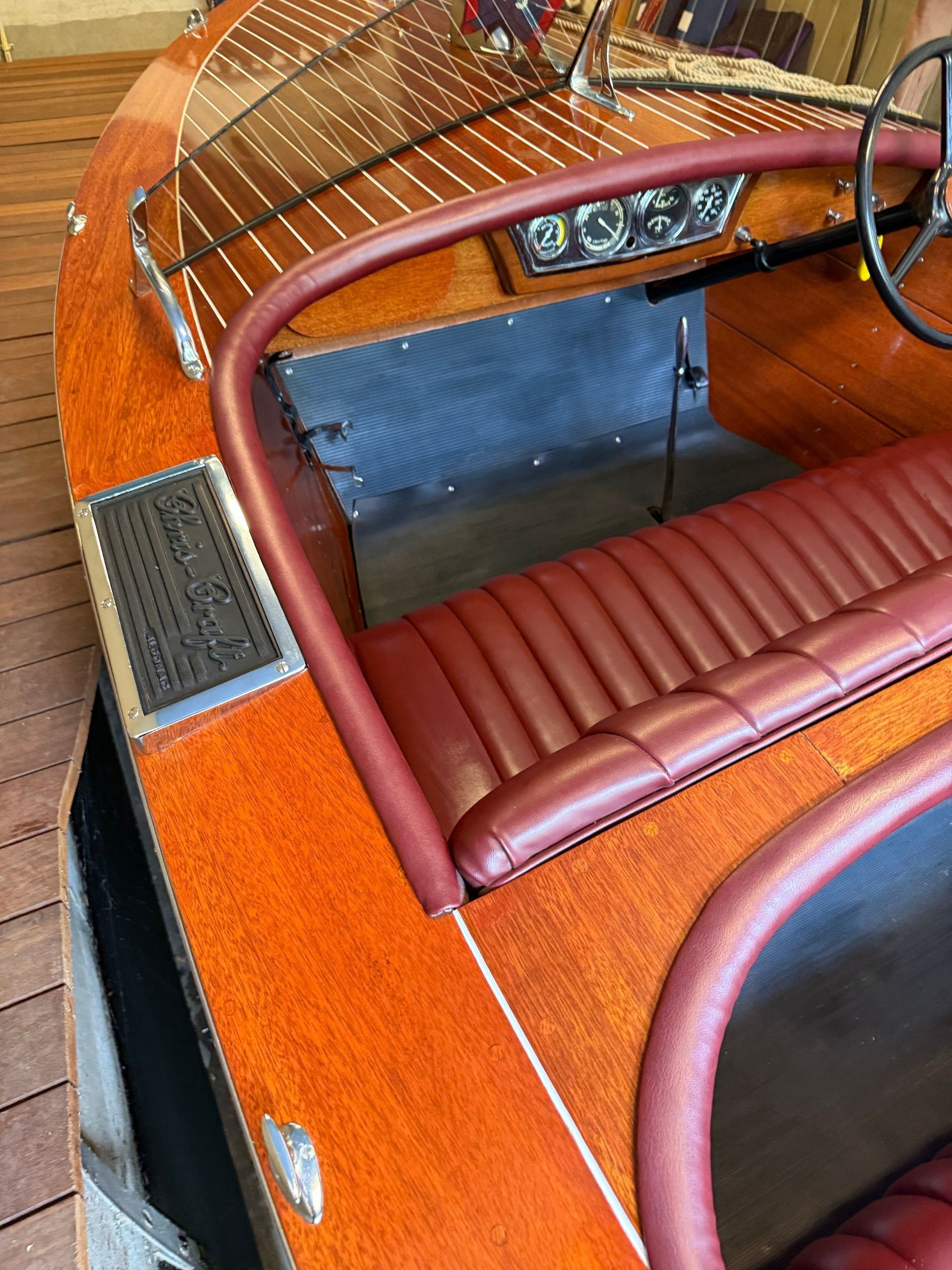 Orange wooden speedboat cockpit with red-brown bench seats and chrome steering wheel.