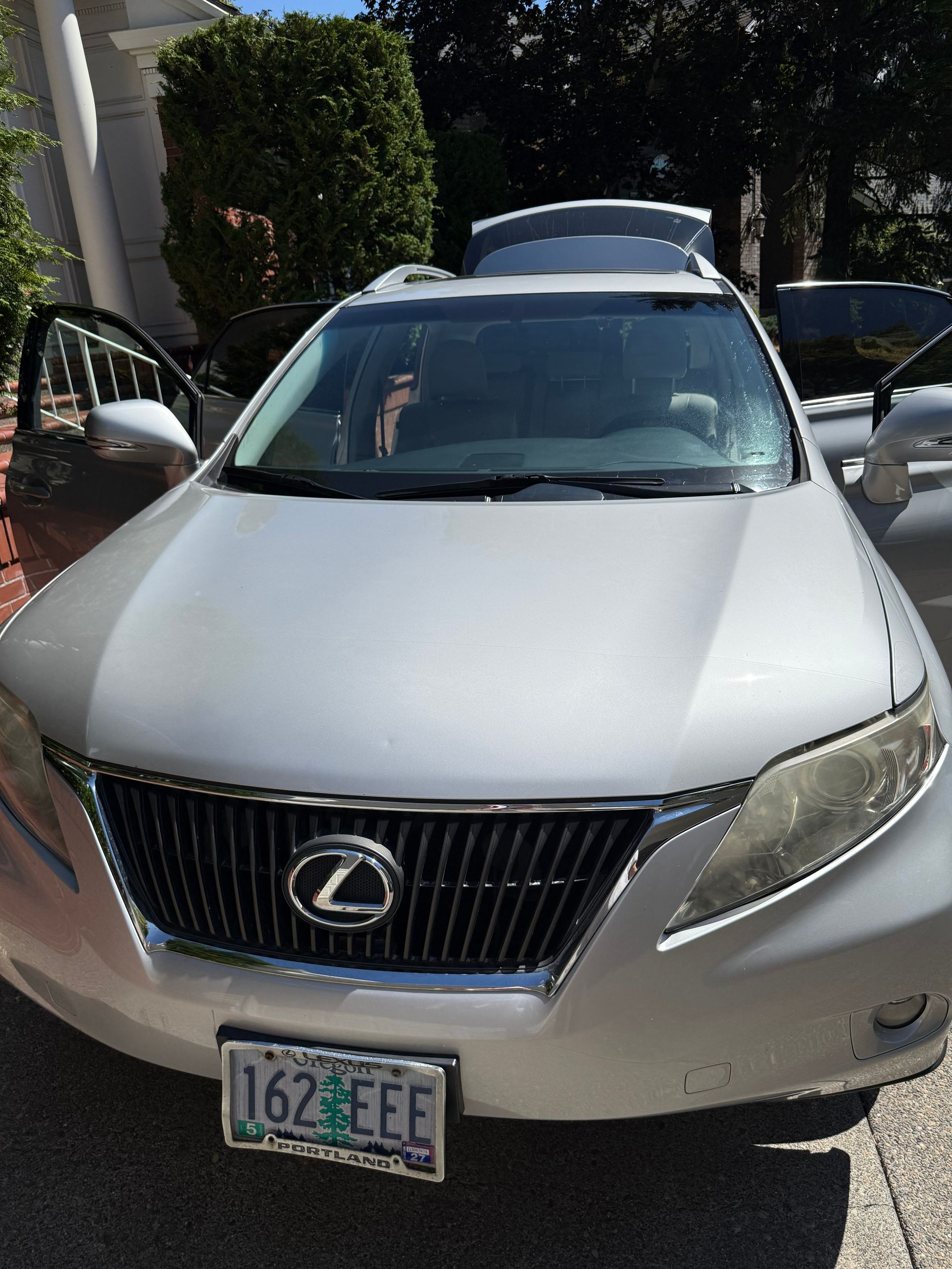 Front view of a silver Lexus SUV parked outdoors with doors open and a California license plate.