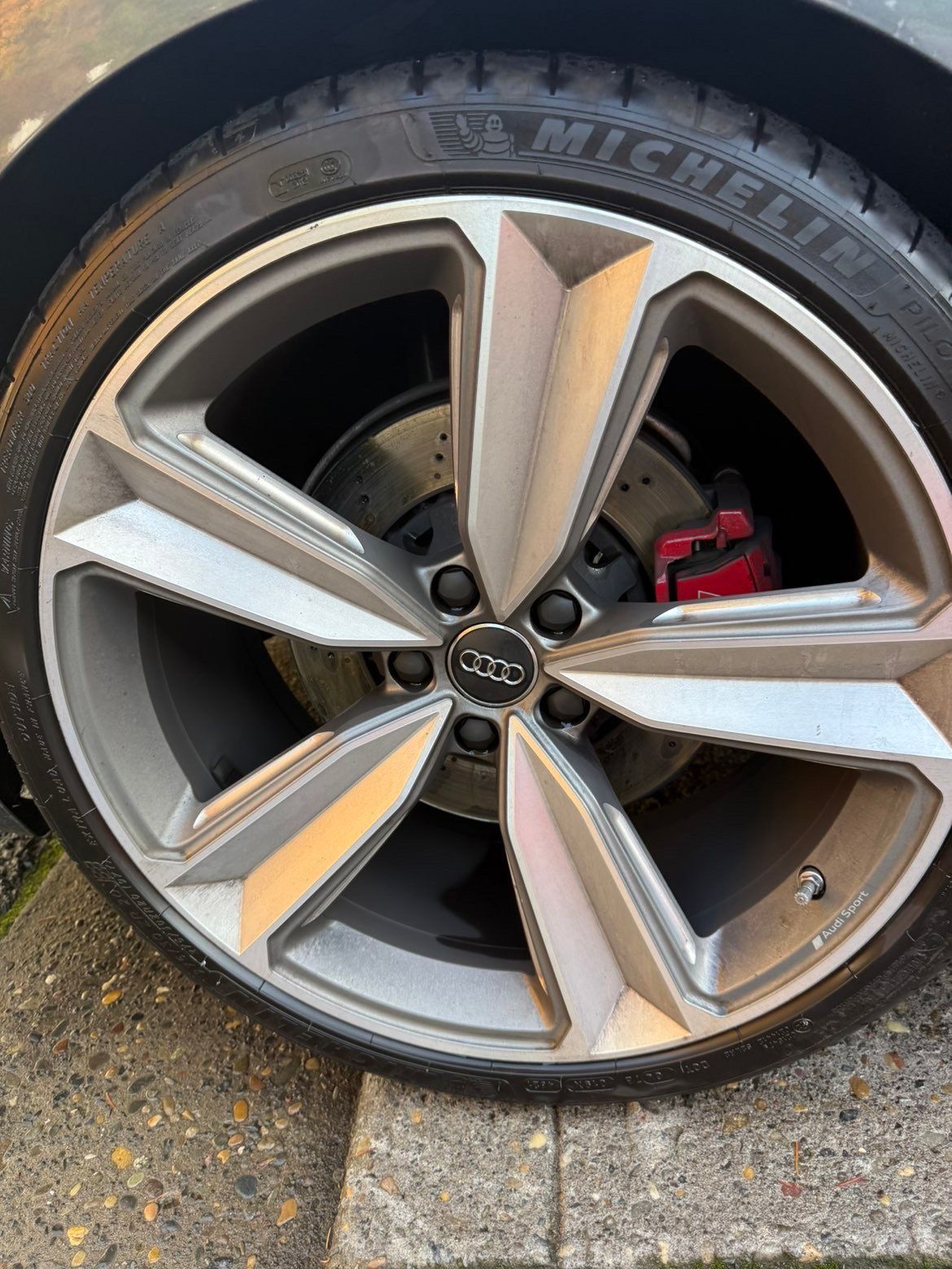 Close-up of a silver Audi alloy wheel with a red brake caliper on a car.