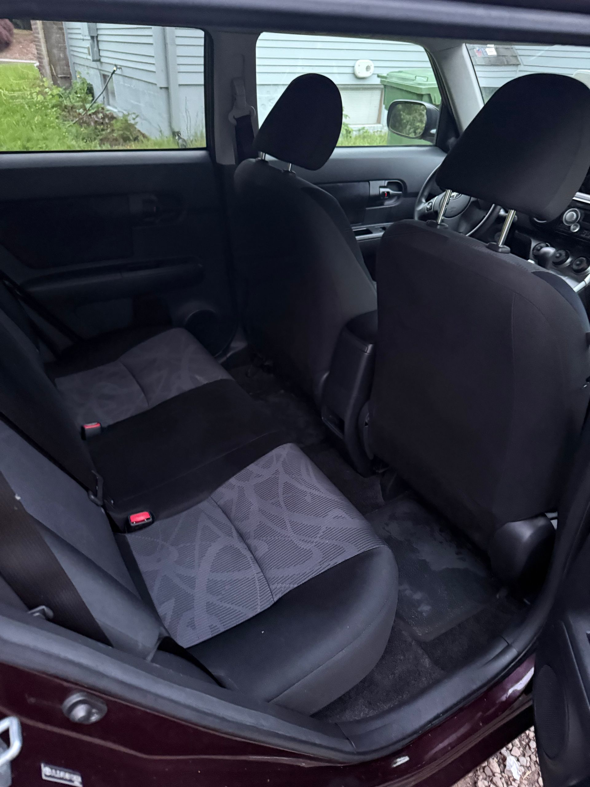 Car interior with folded rear seat, dark upholstery, and a gray blanket on the back seat.