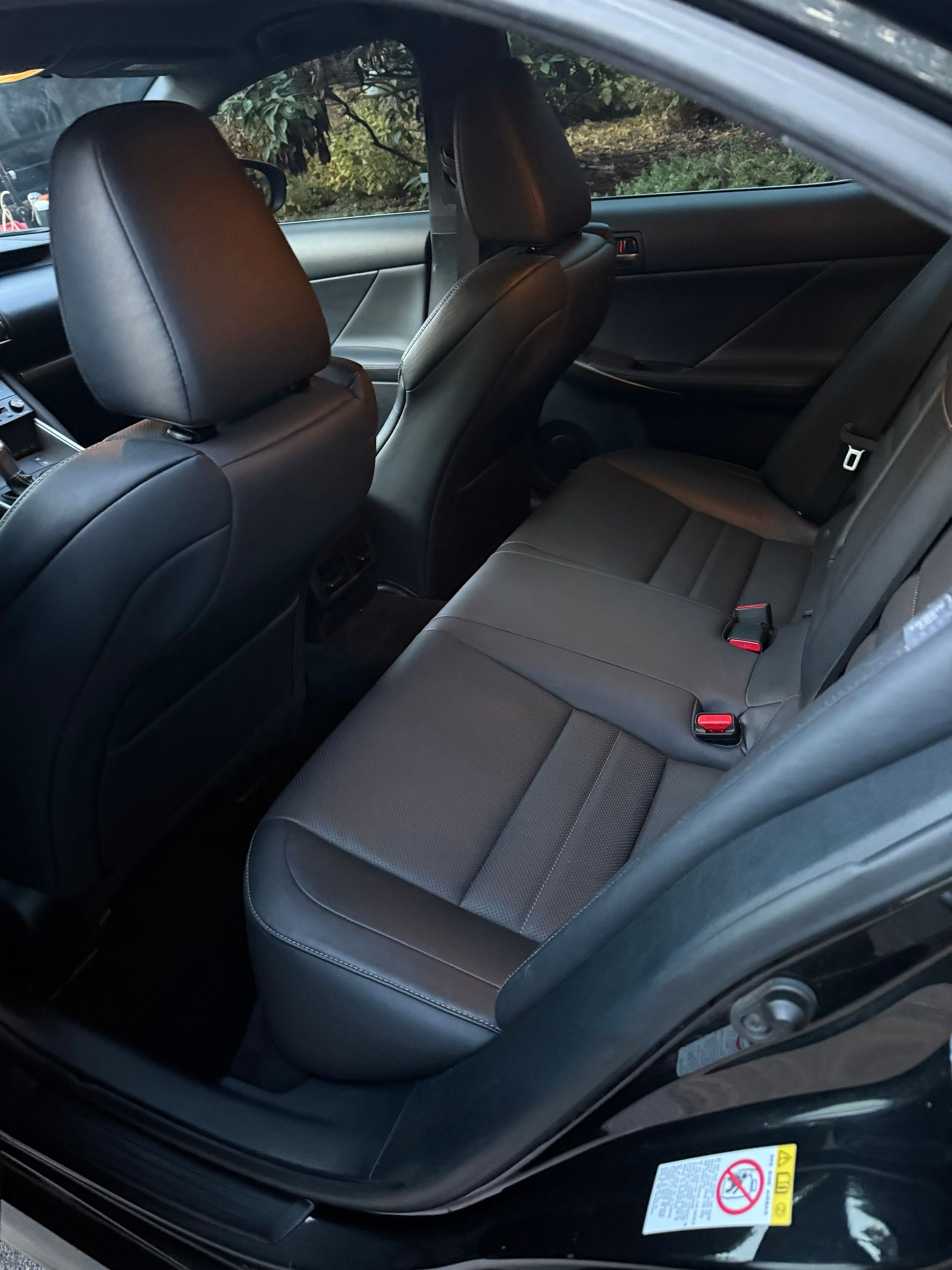 Black leather car back seat and front passenger seat interior with folded rear armrest.