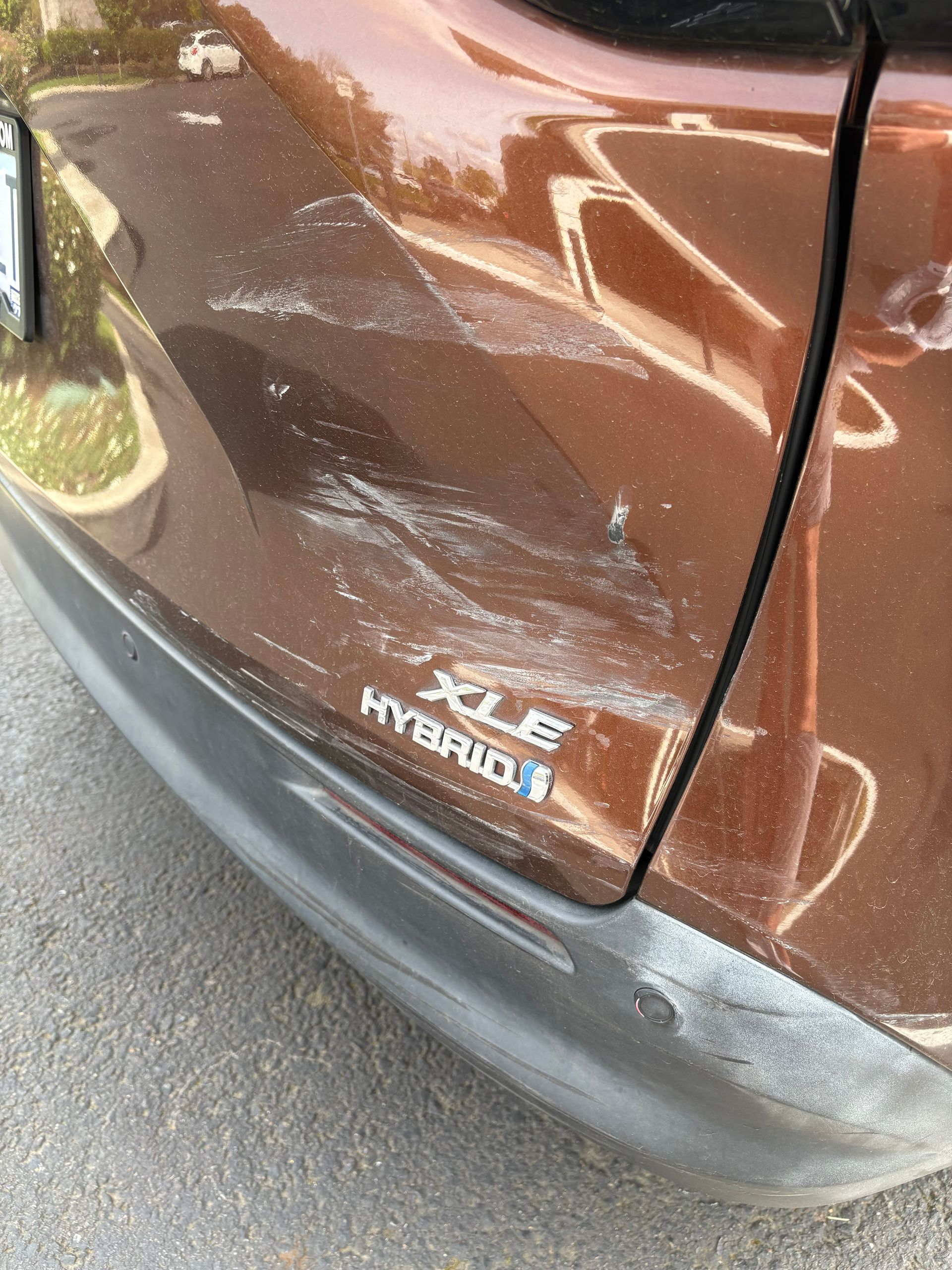 Brown car side panel with HYBRID badge and visible scuffing on the lower bumper