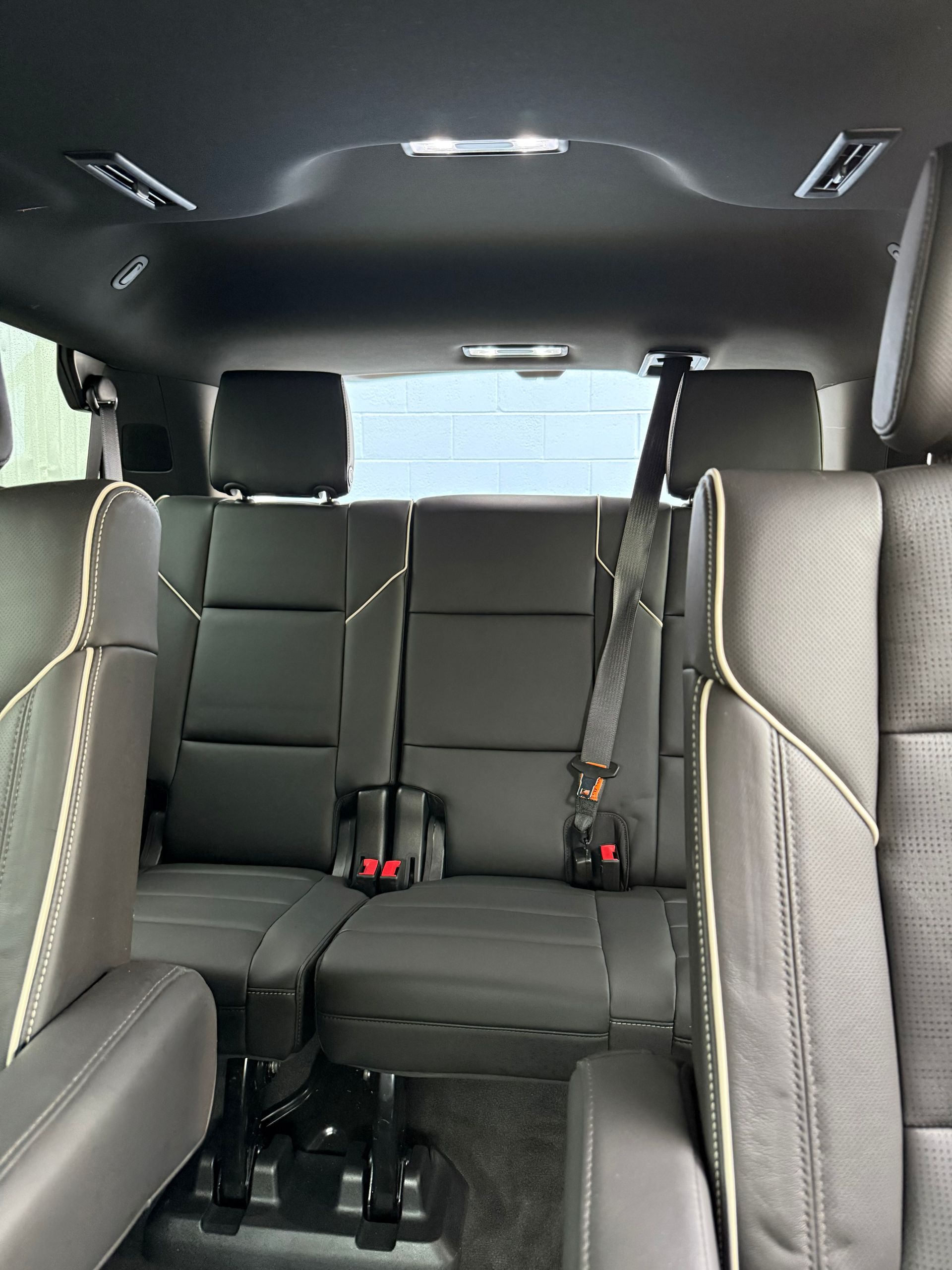 Empty black car interior with rear bench seats and gray trim, viewed from the back to the front