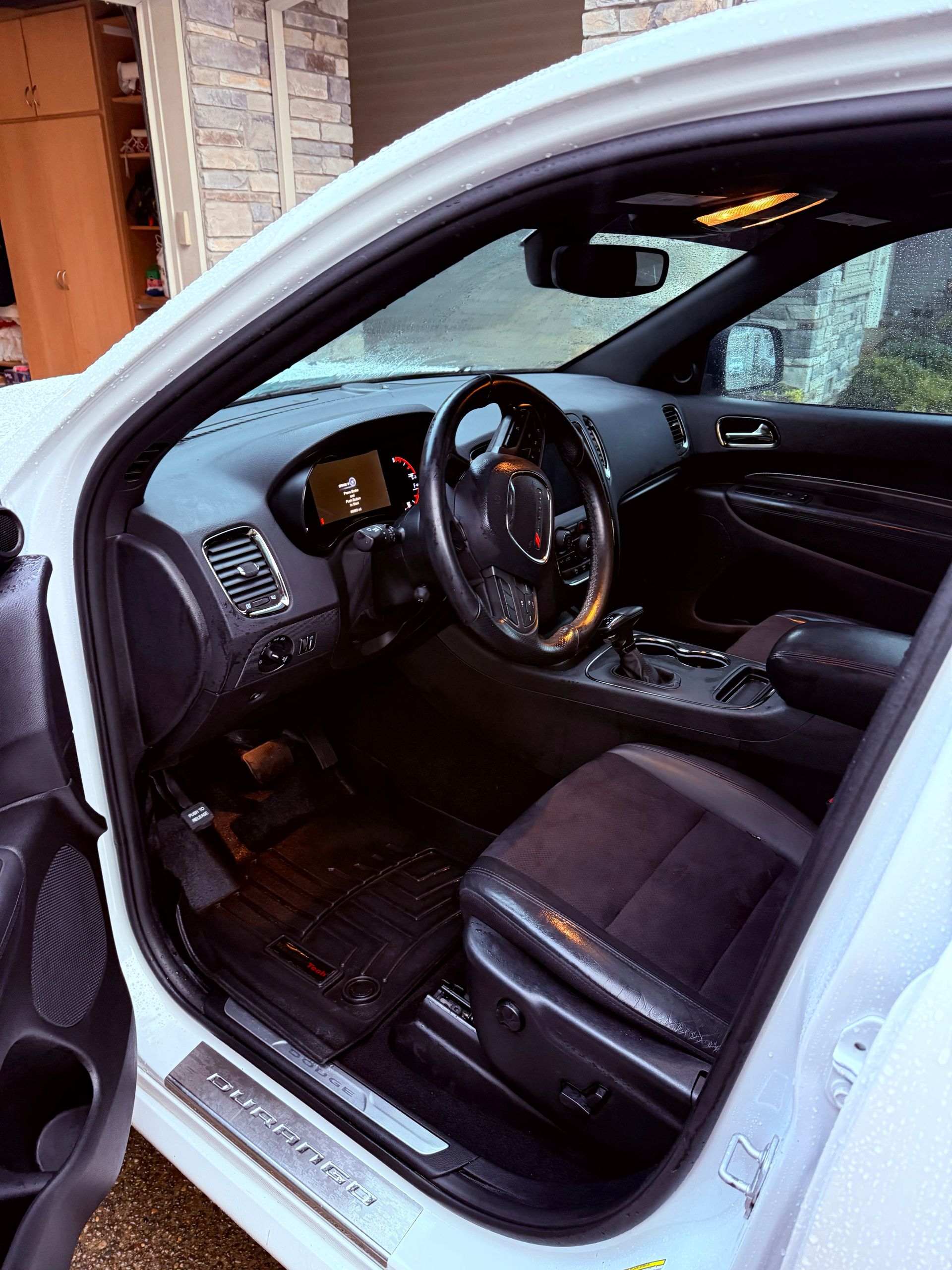 Open car door showing black leather driver's seat and dashboard interior