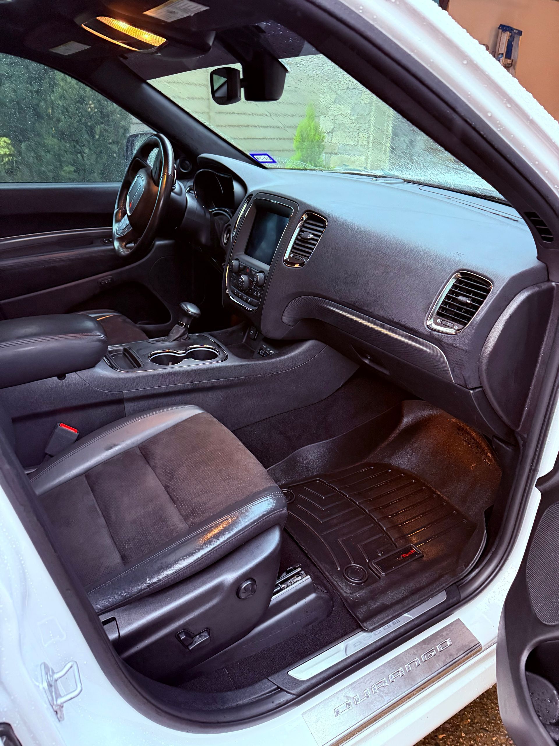 Open car interior with black seats, dashboard, steering wheel, and driver-side door visible.