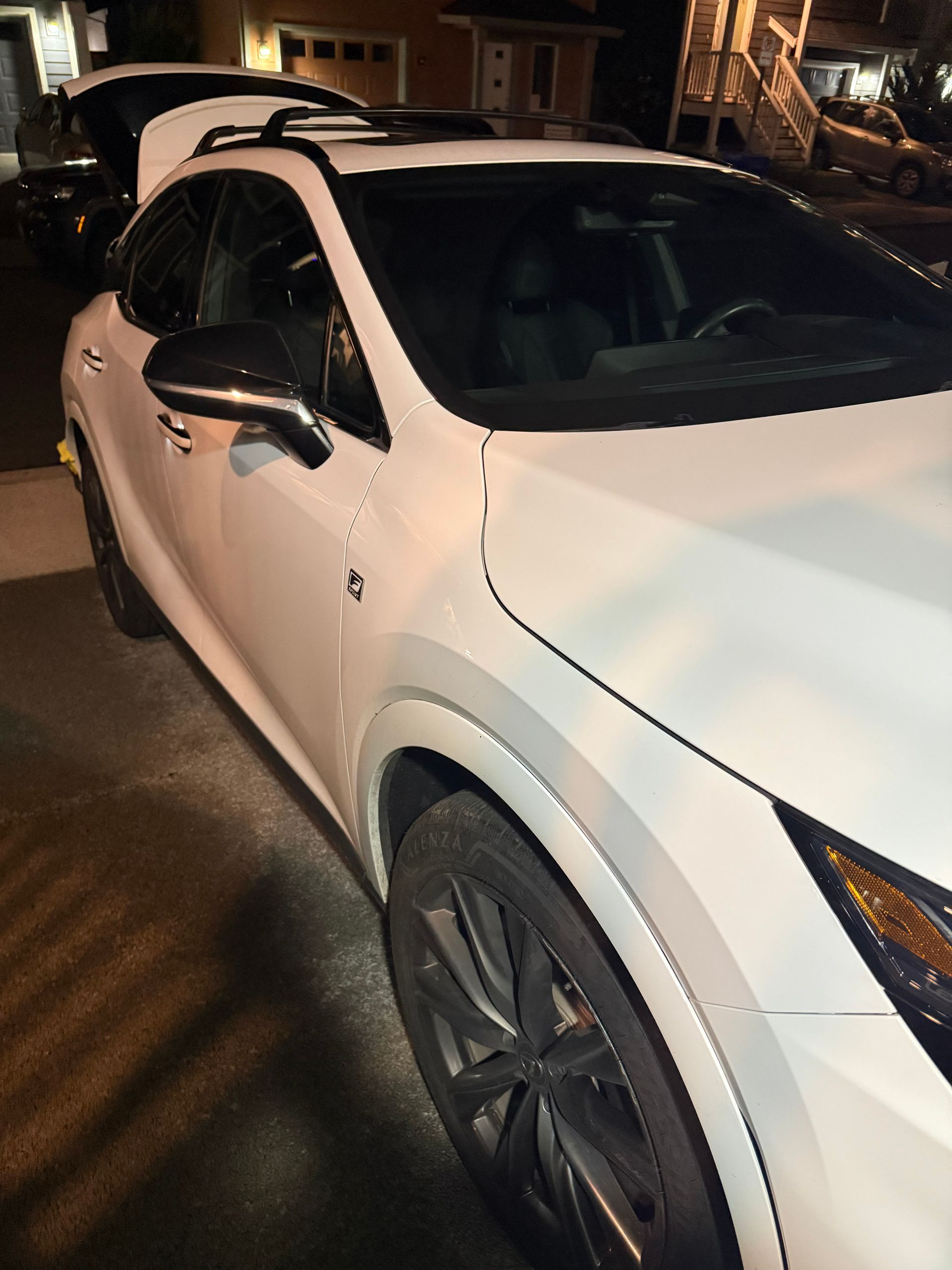 White SUV parked on a dimly lit street at night, front-left view.