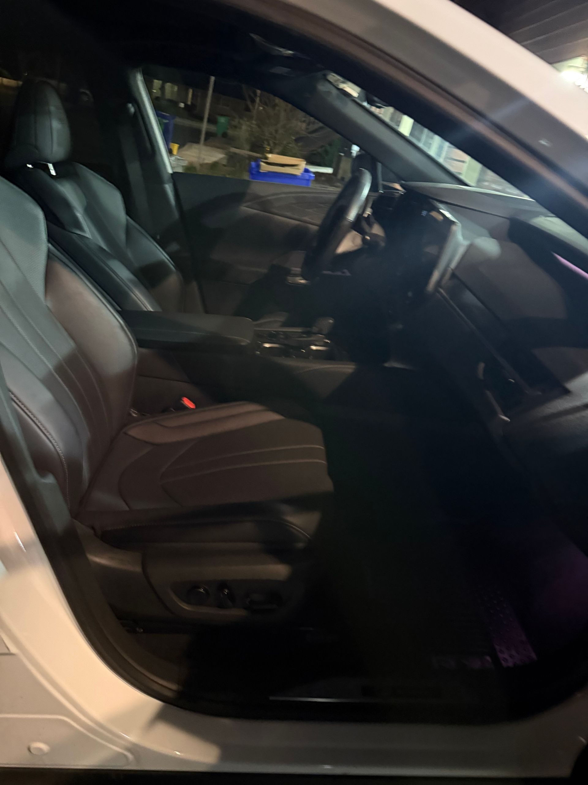 Interior of a silver car with black leather seats and steering wheel, viewed through the open door
