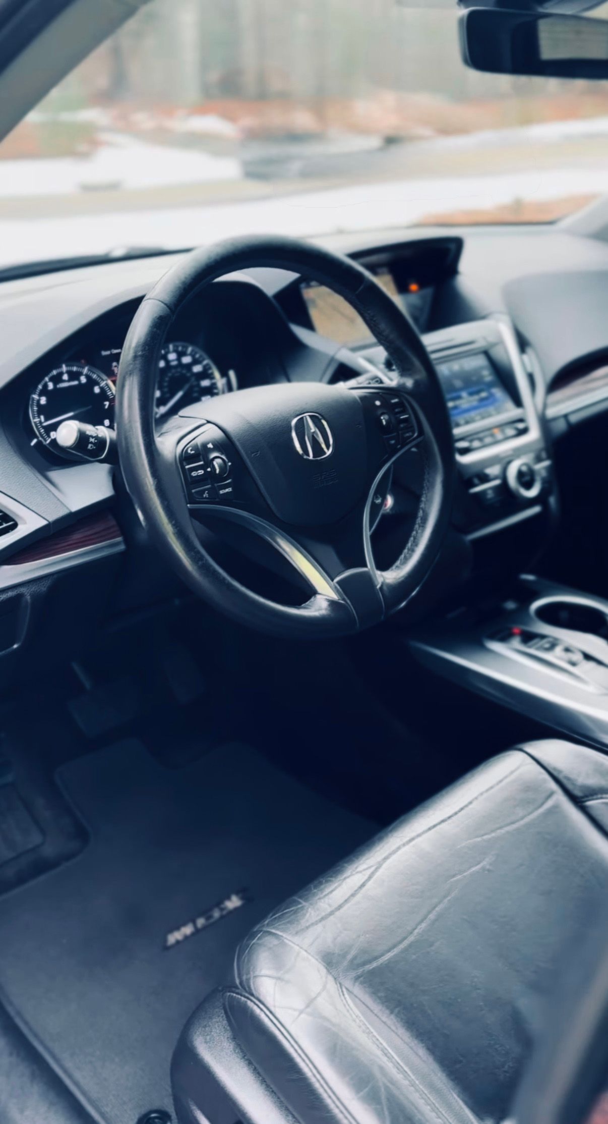 Car interior with black leather seats and steering wheel, viewed from the driver’s seat