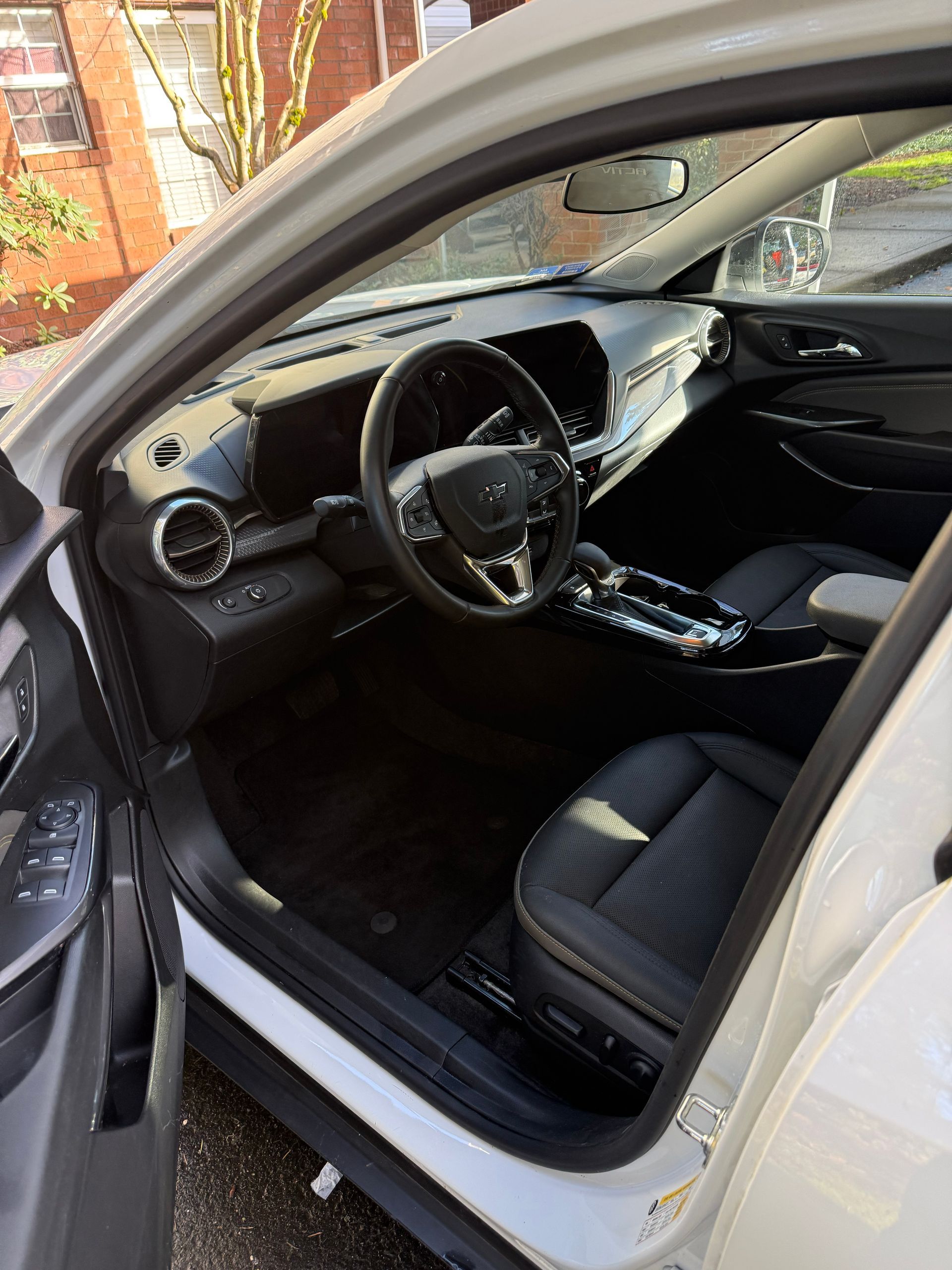 Open car door showing a black interior with steering wheel and front seats