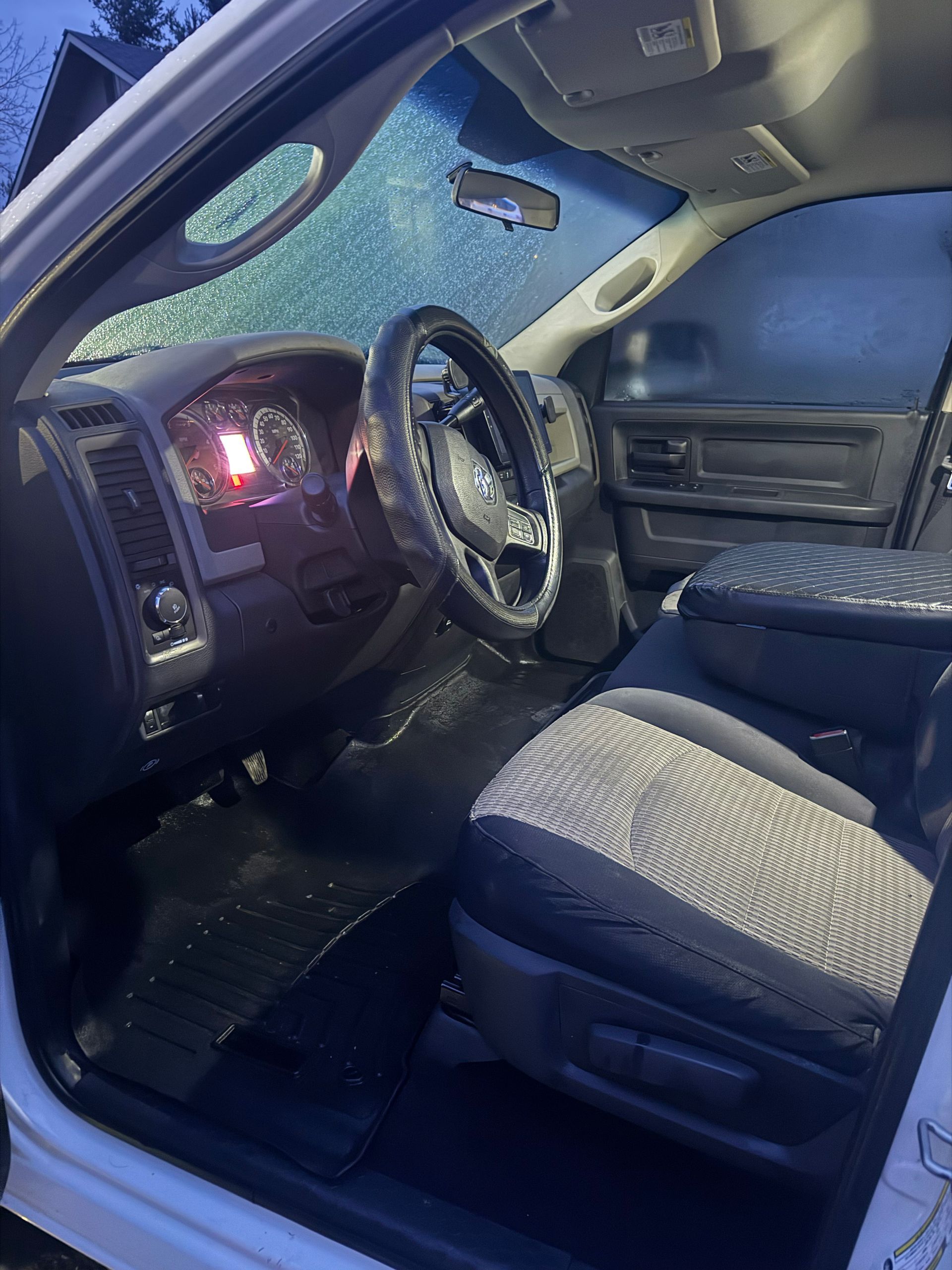 Interior of a blue car with the driver’s door open, showing the steering wheel and front seats.