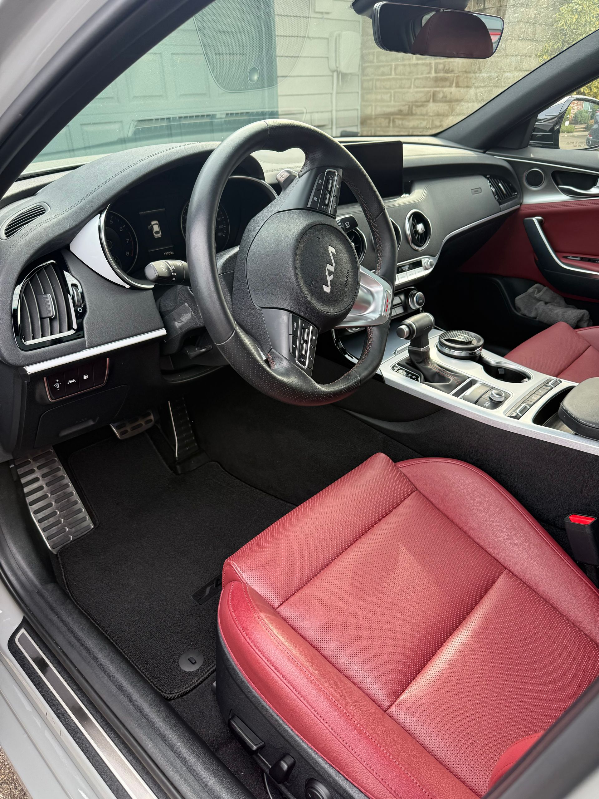 Car interior with red seats, black dashboard, and steering wheel, viewed from the driver’s side