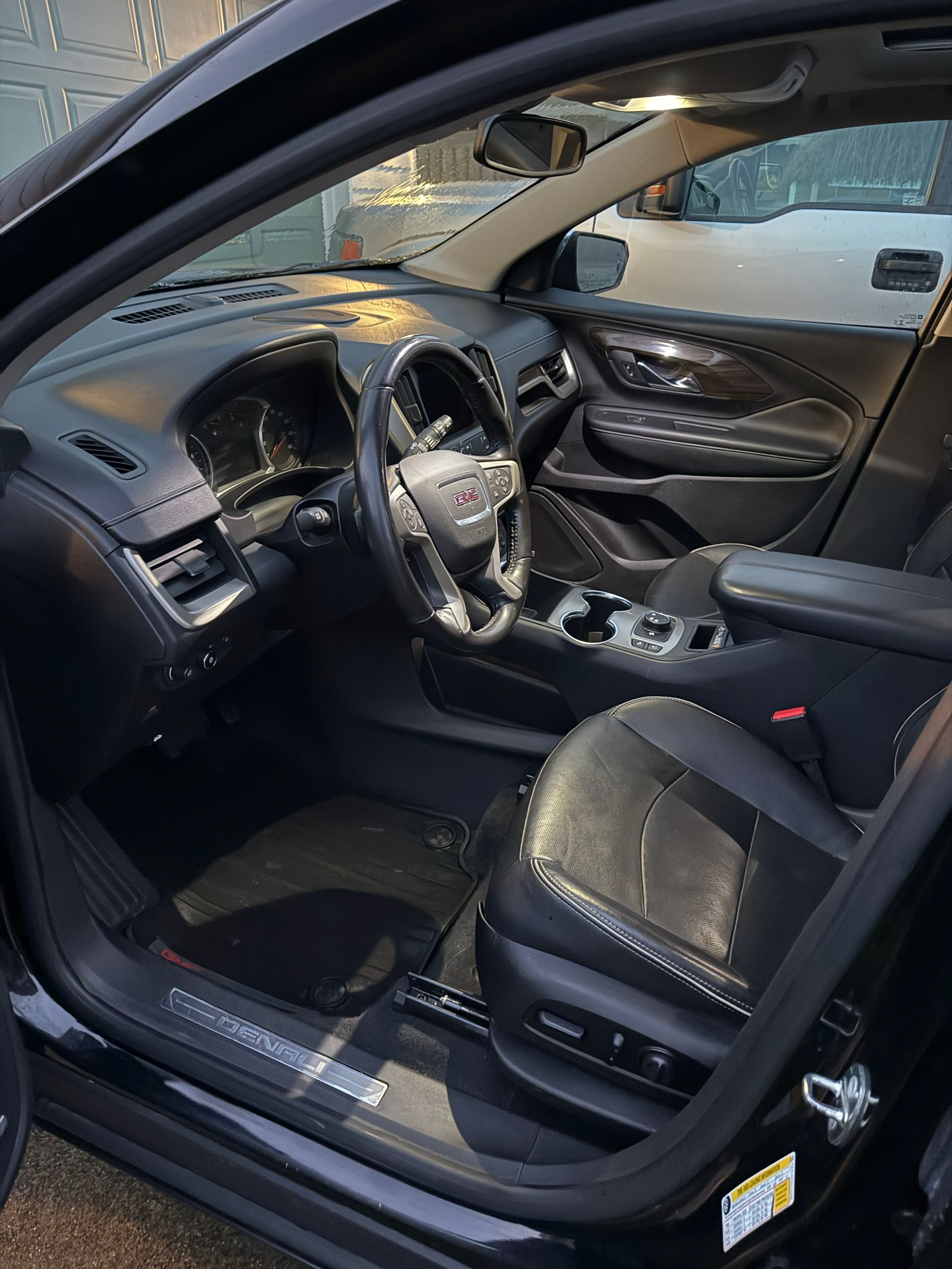 Black car interior with open driver’s door, showing dashboard, steering wheel, and front seats