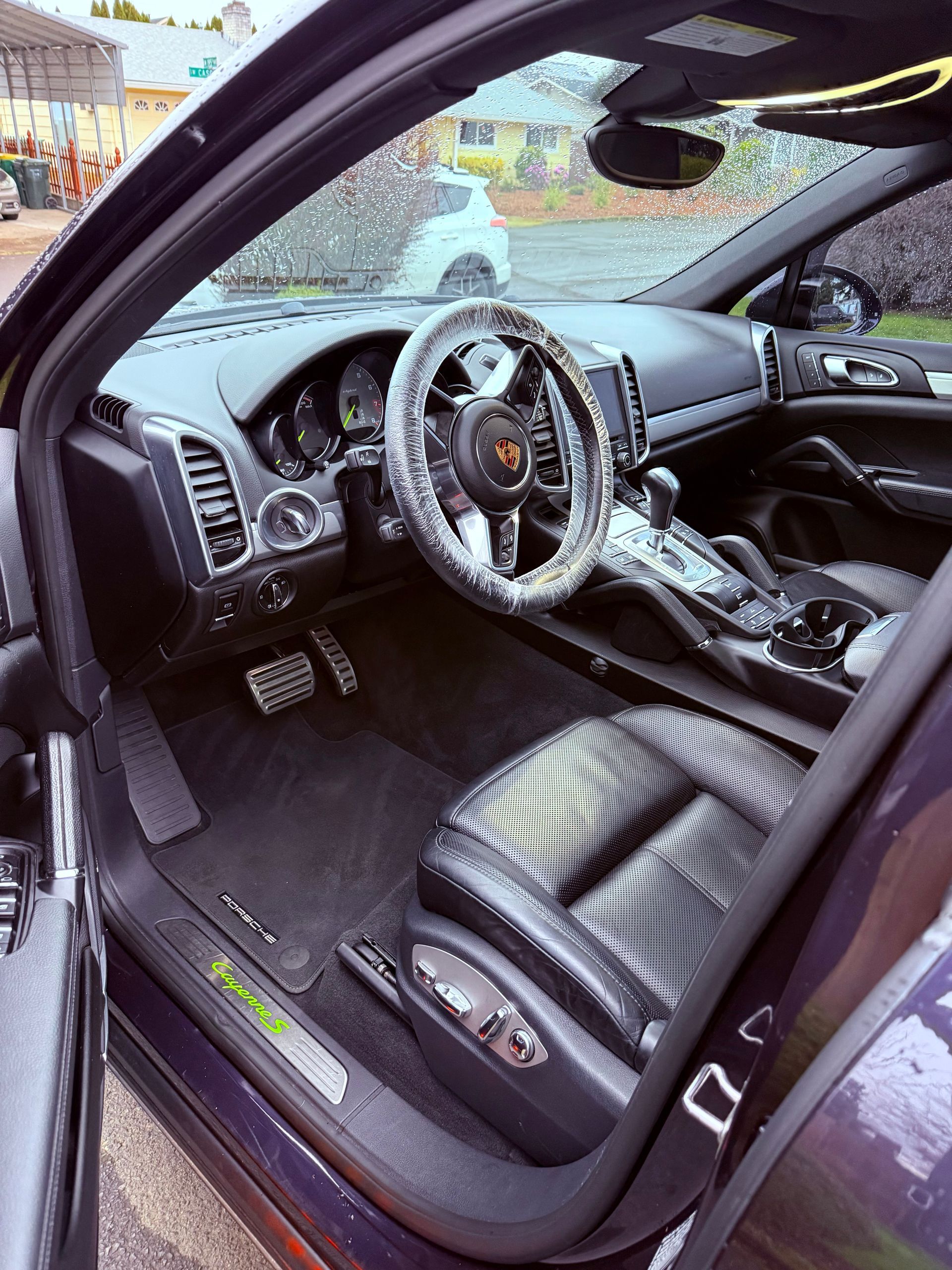 Car interior with a custom steering wheel, black leather seats, and a shattered windshield.