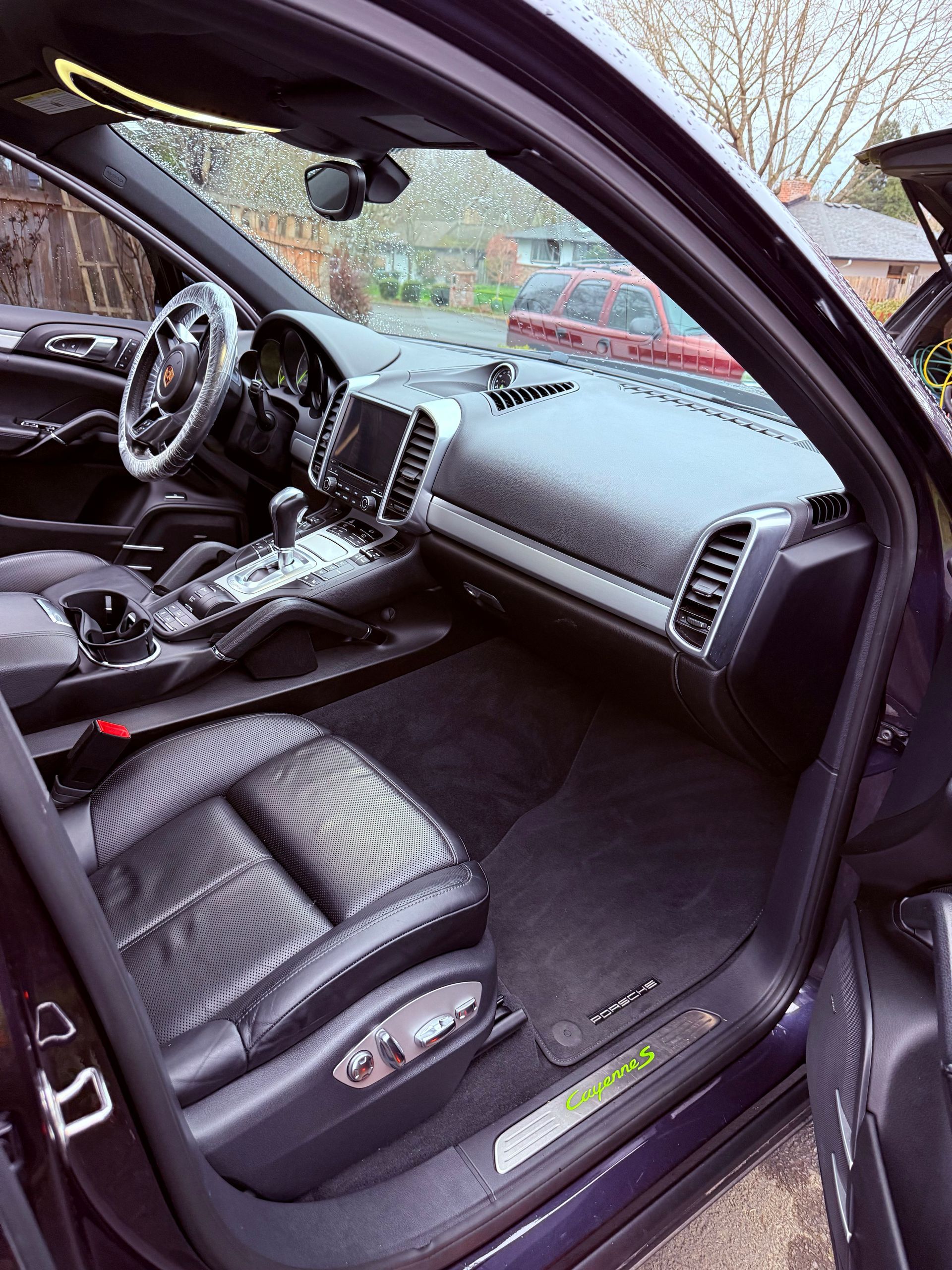 Black car interior with open door, showing dashboard, center console, and leather seat.