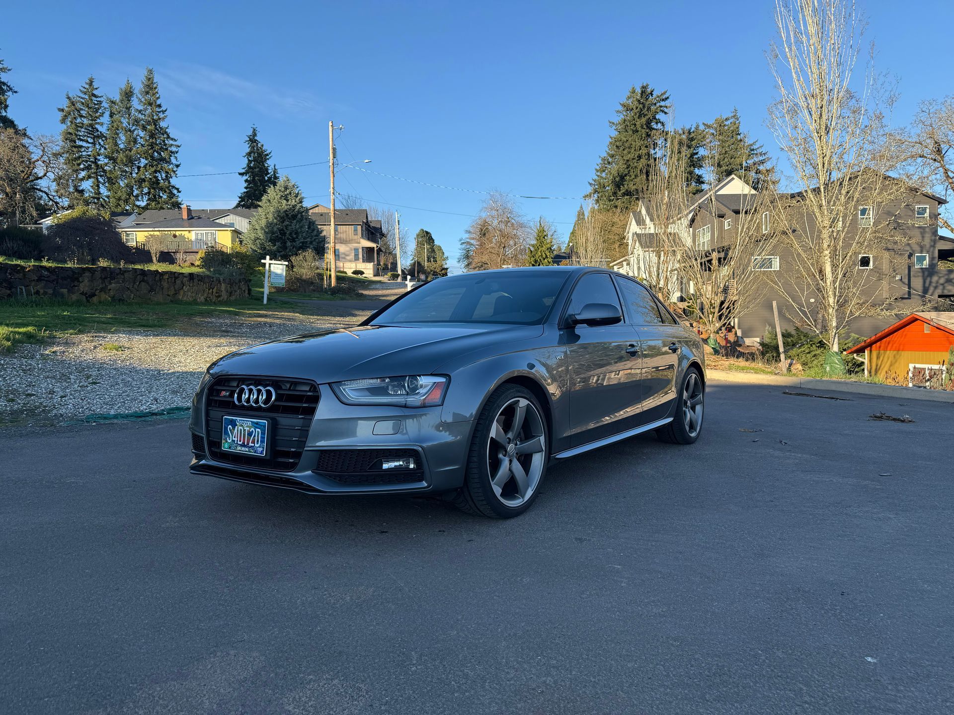 Gray Audi sedan parked on a street in a suburban neighborhood on a sunny day
