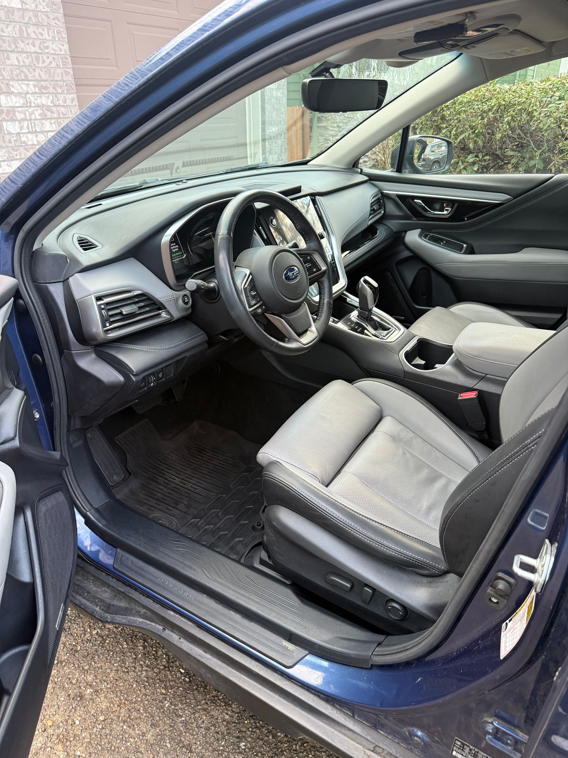 Blue car interior with driver’s door open, showing steering wheel and gray seats.