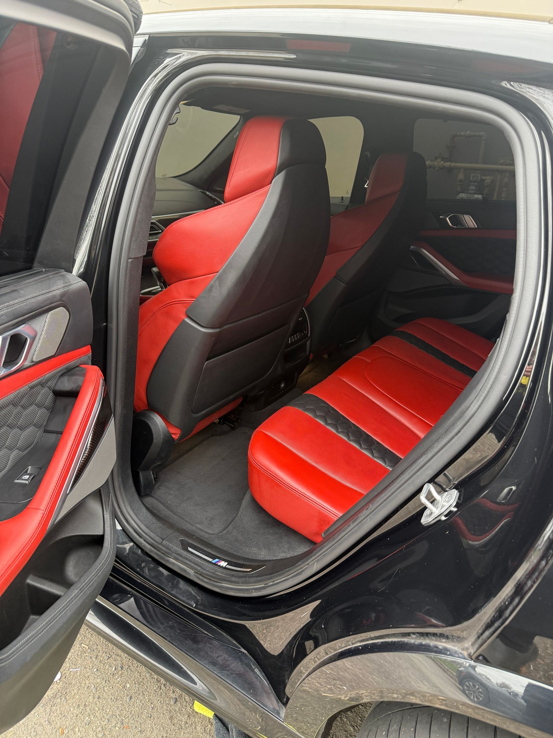 Open car door showing red-and-black seat covers and interior of a black vehicle
