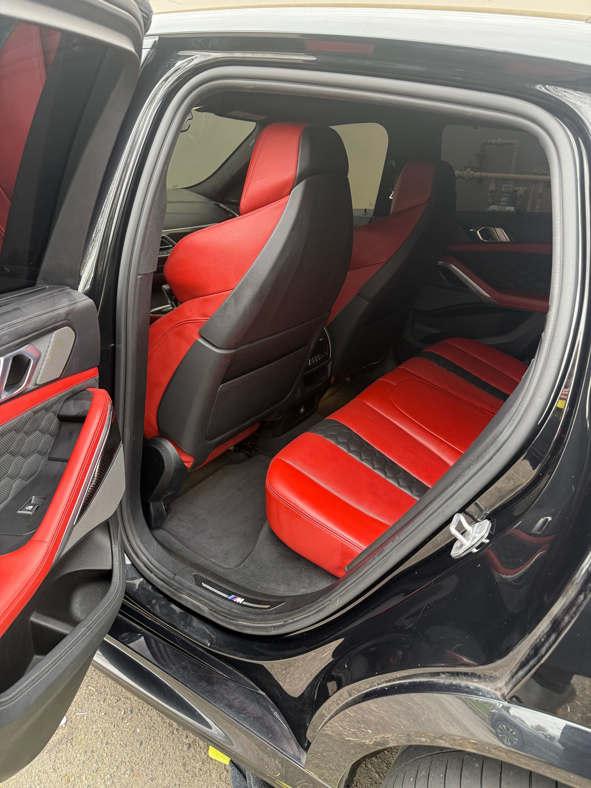 Open car door revealing black-and-red custom leather seats and interior trim.