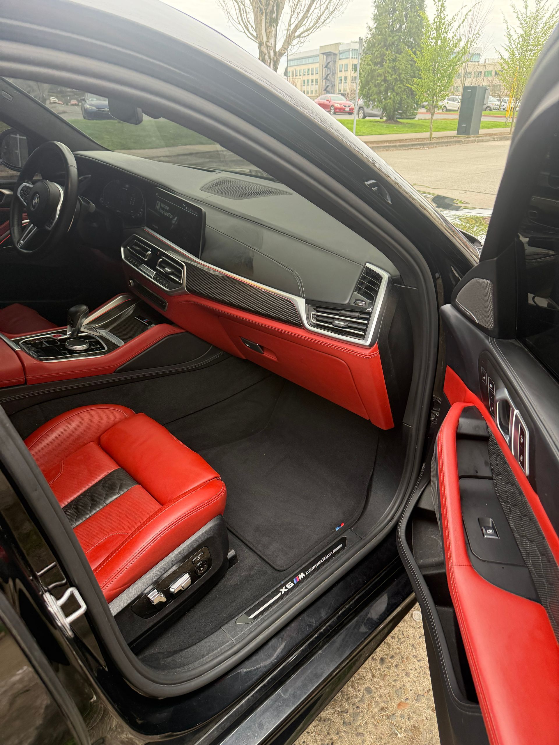 Luxury car interior with red leather seats and black trim, viewed through the open door