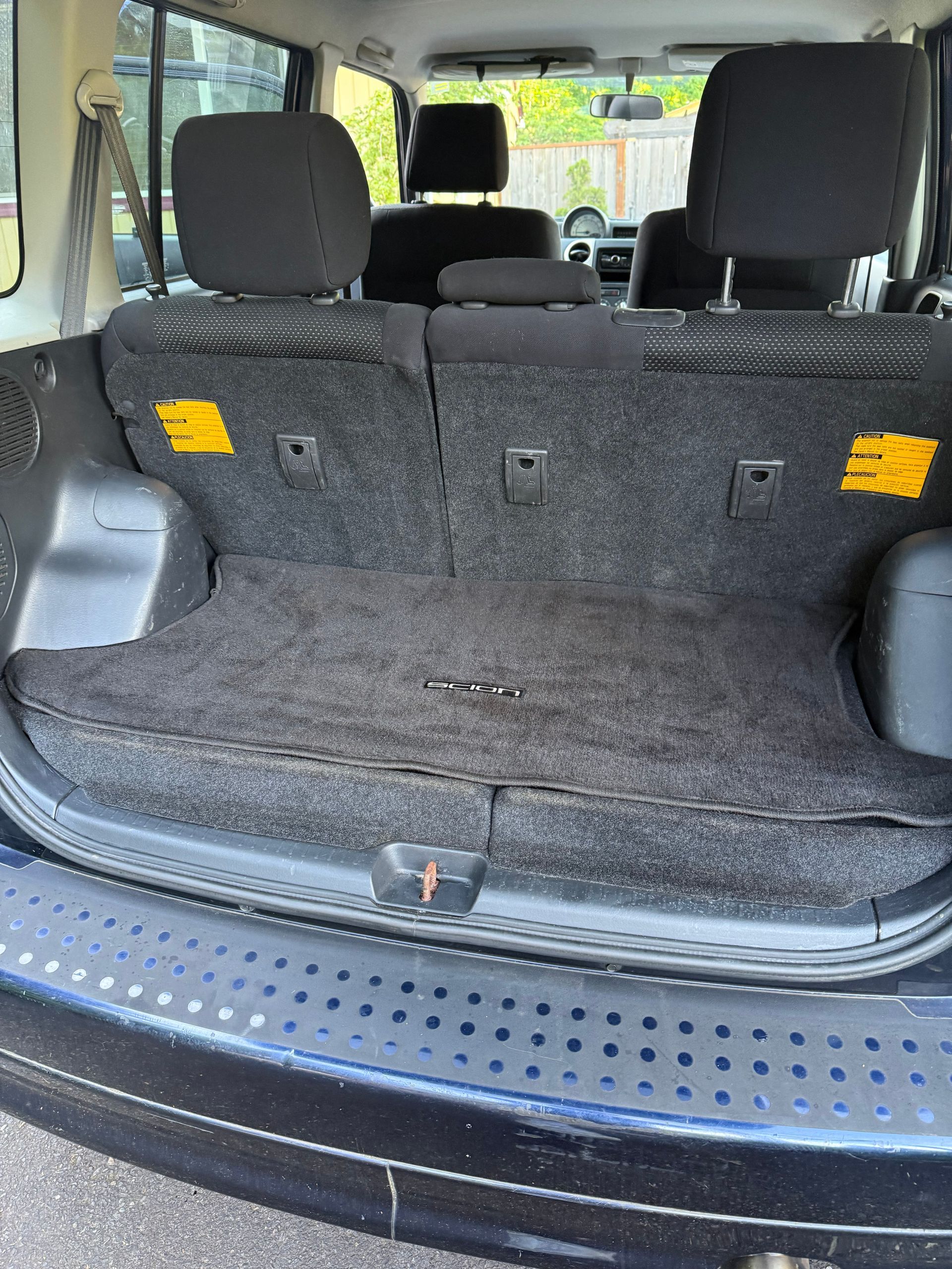 Car trunk with the rear seats folded down, showing a black carpeted cargo area and gray headrests.