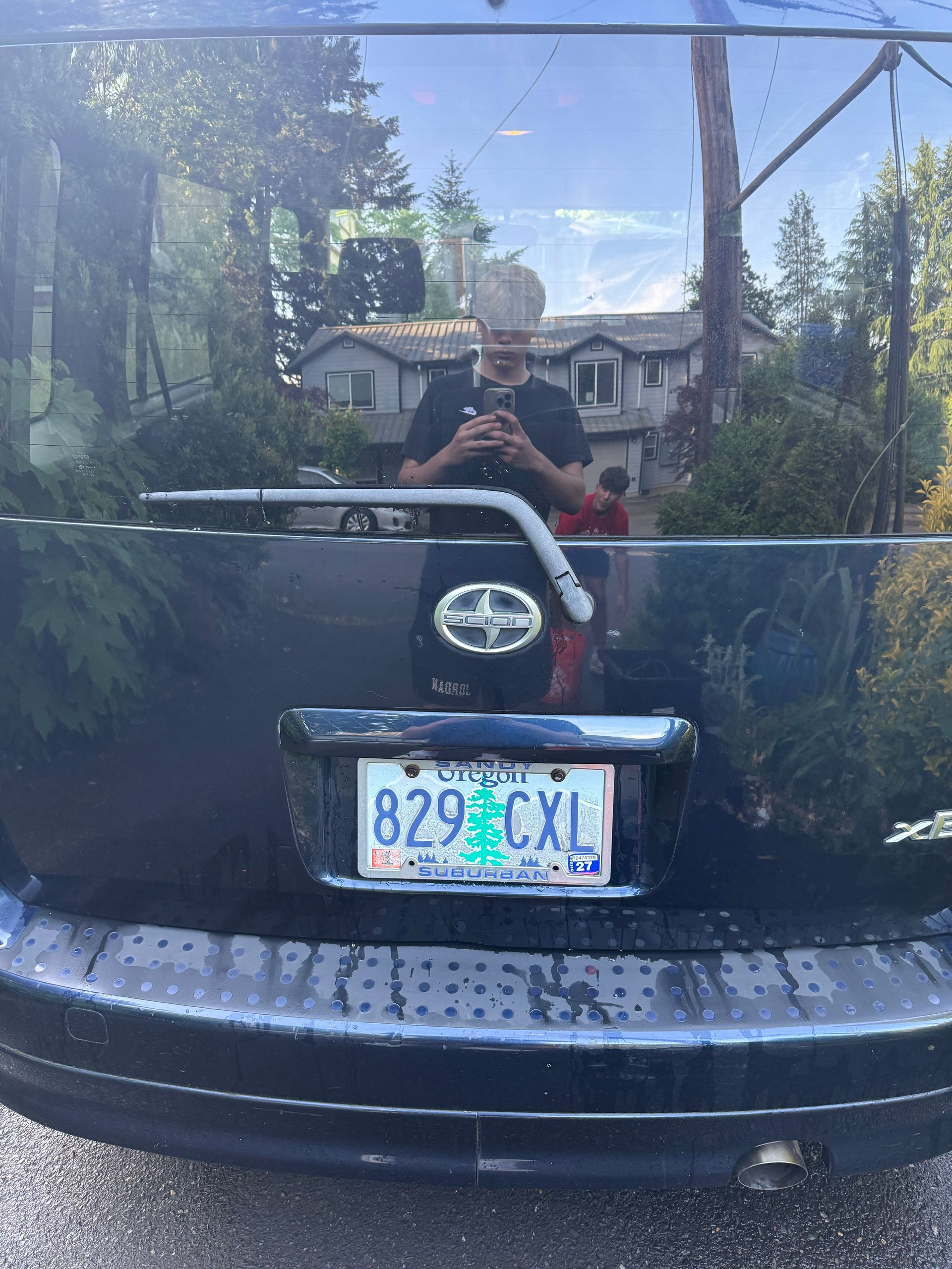 Rear view of a black Toyota SUV with a Connecticut license plate parked in a driveway, reflecting a person taking the photo.