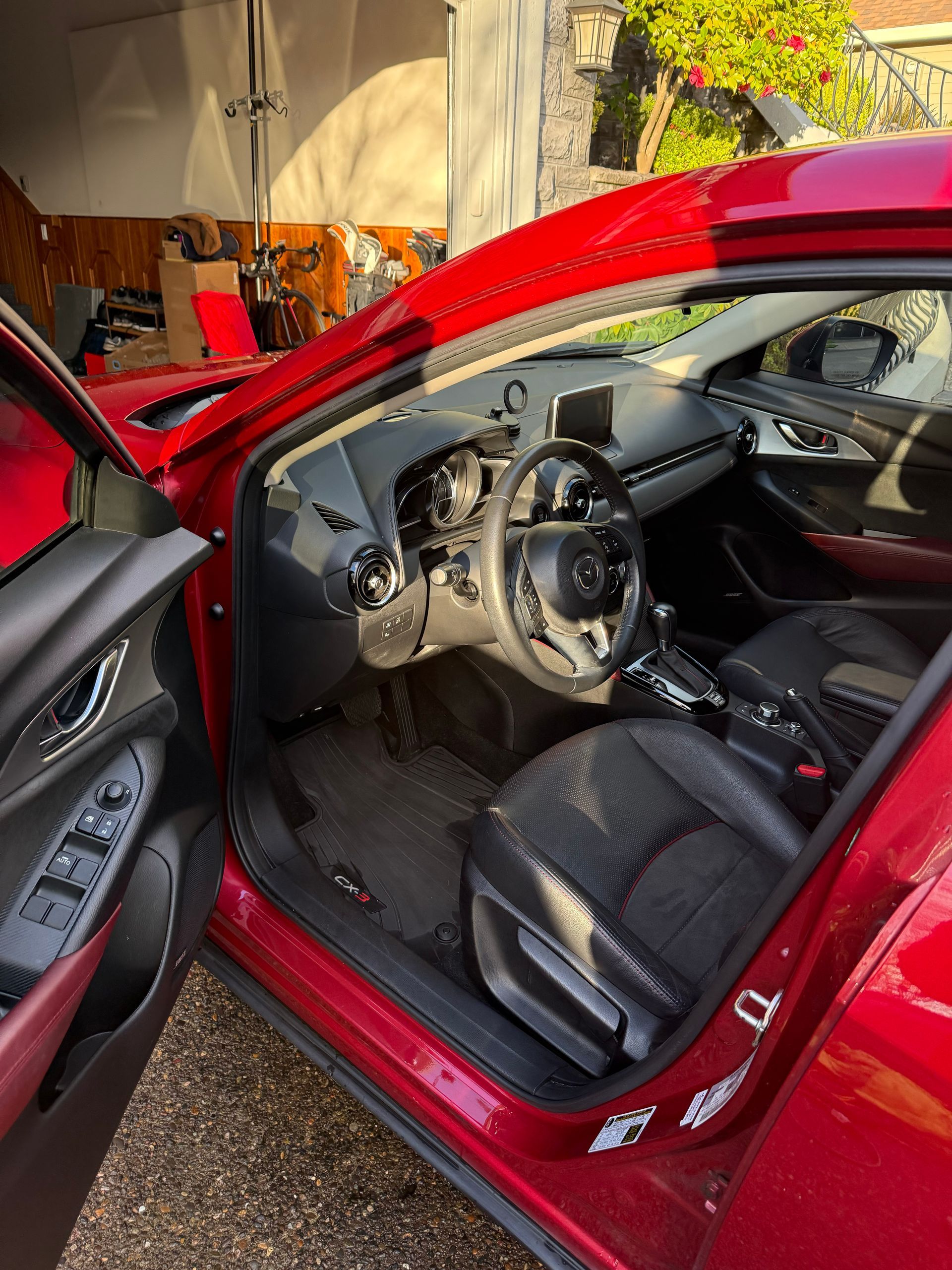 Open red car with black interior and visible dashboard, parked outdoors in sunlight