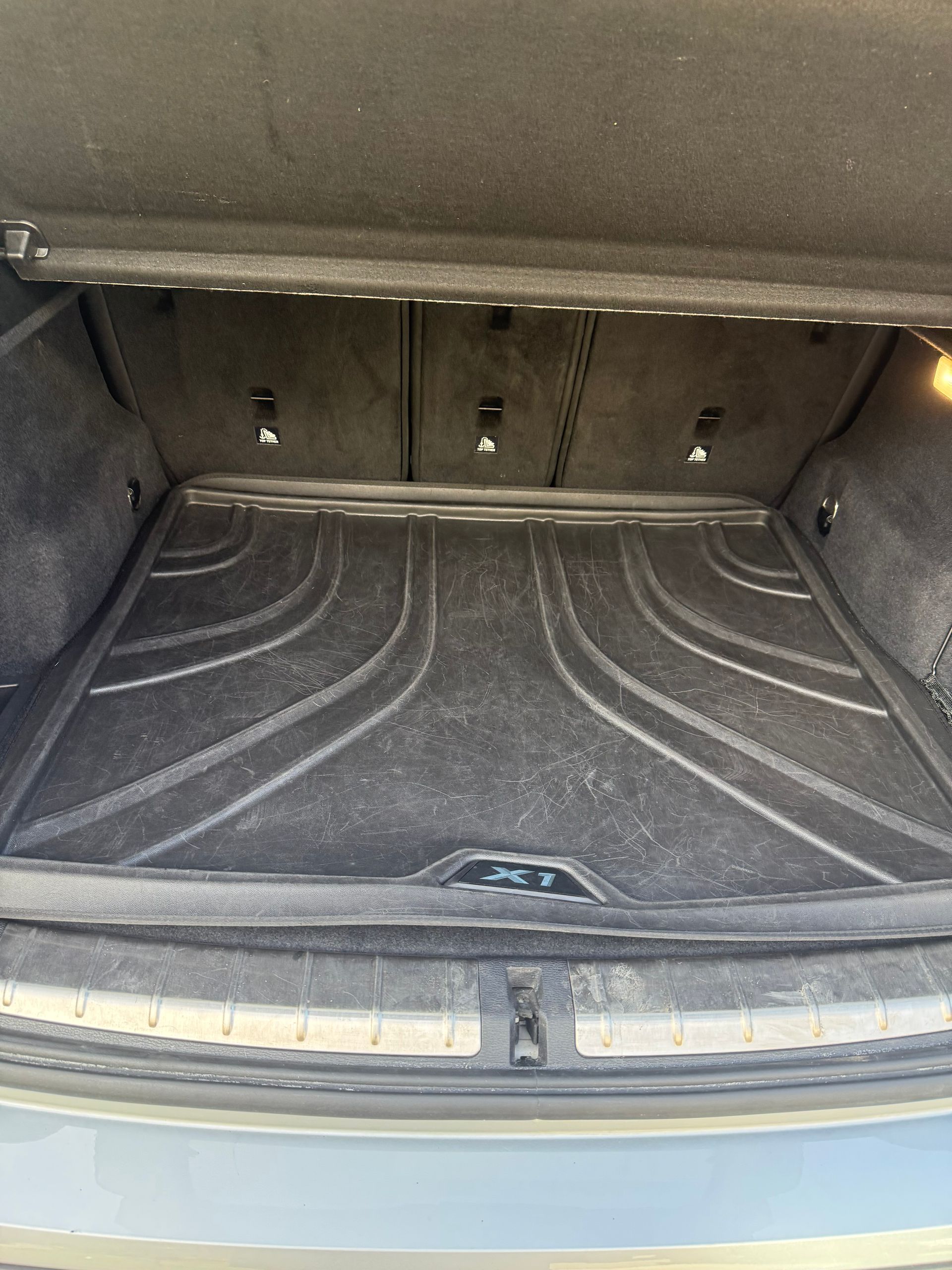 Open car trunk with black cargo mat and grey interior trim
