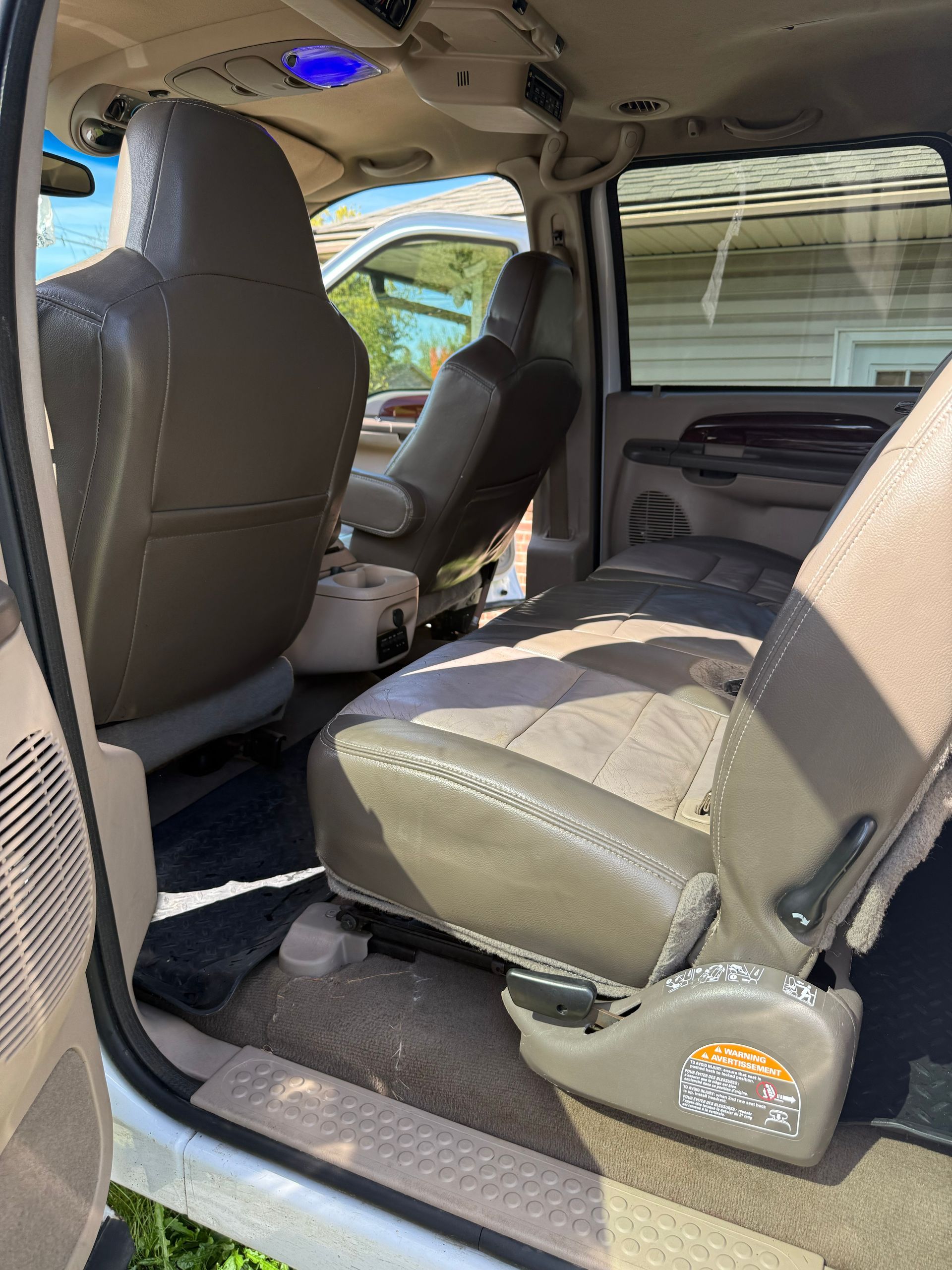 Open vehicle interior with a gray bench seat and front seat visible through the side door.