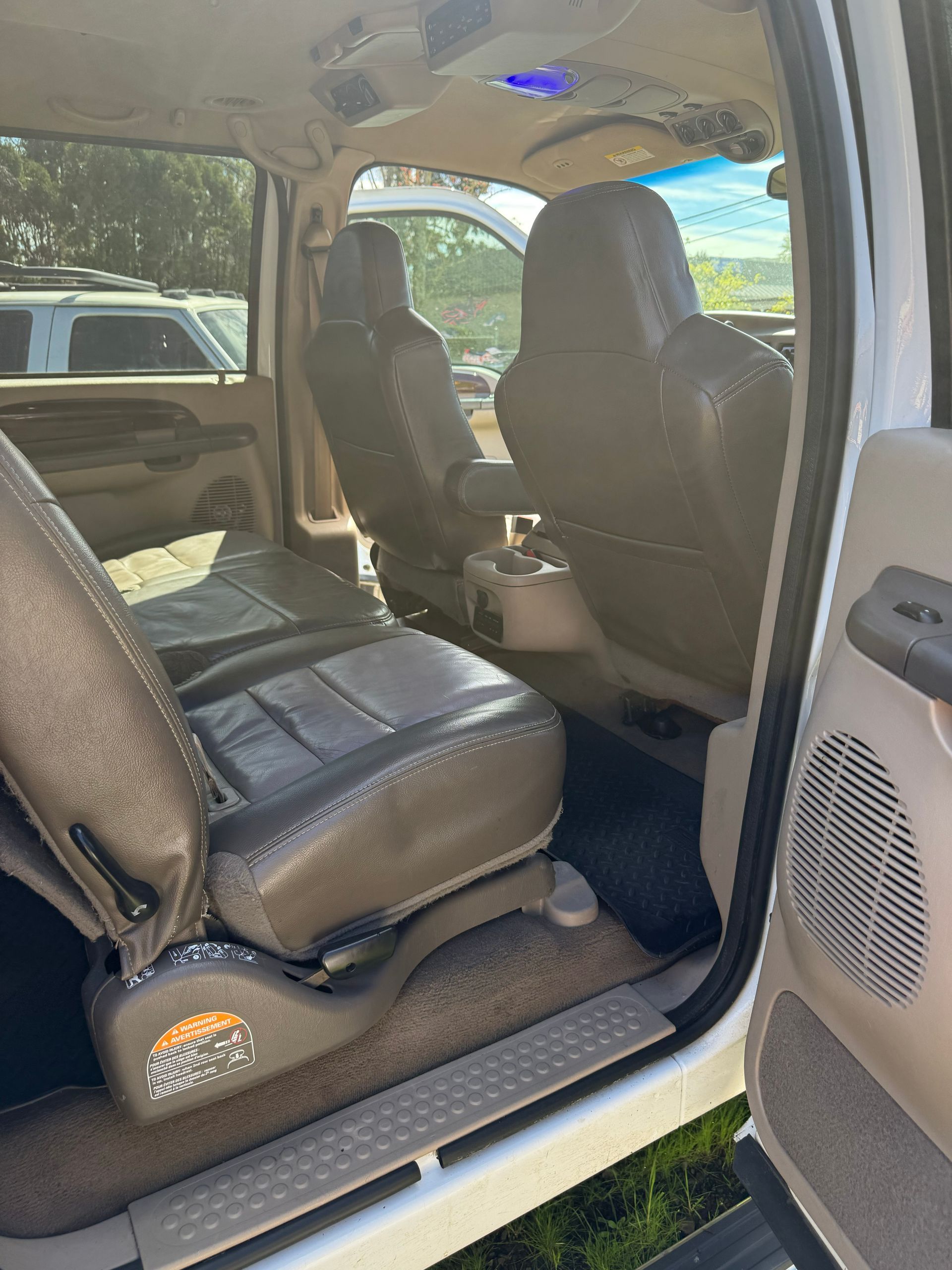 Open car door showing black leather back seats and beige interior.
