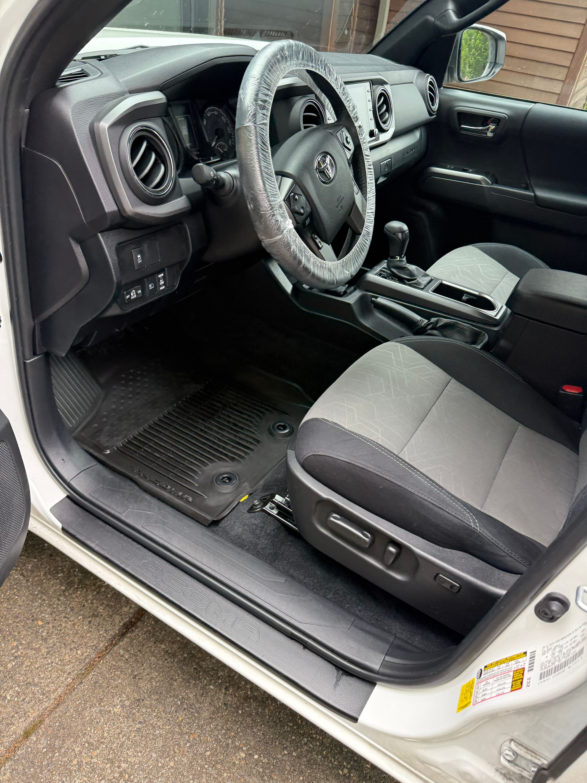 Open driver’s door showing a black and gray car interior with steering wheel and seats