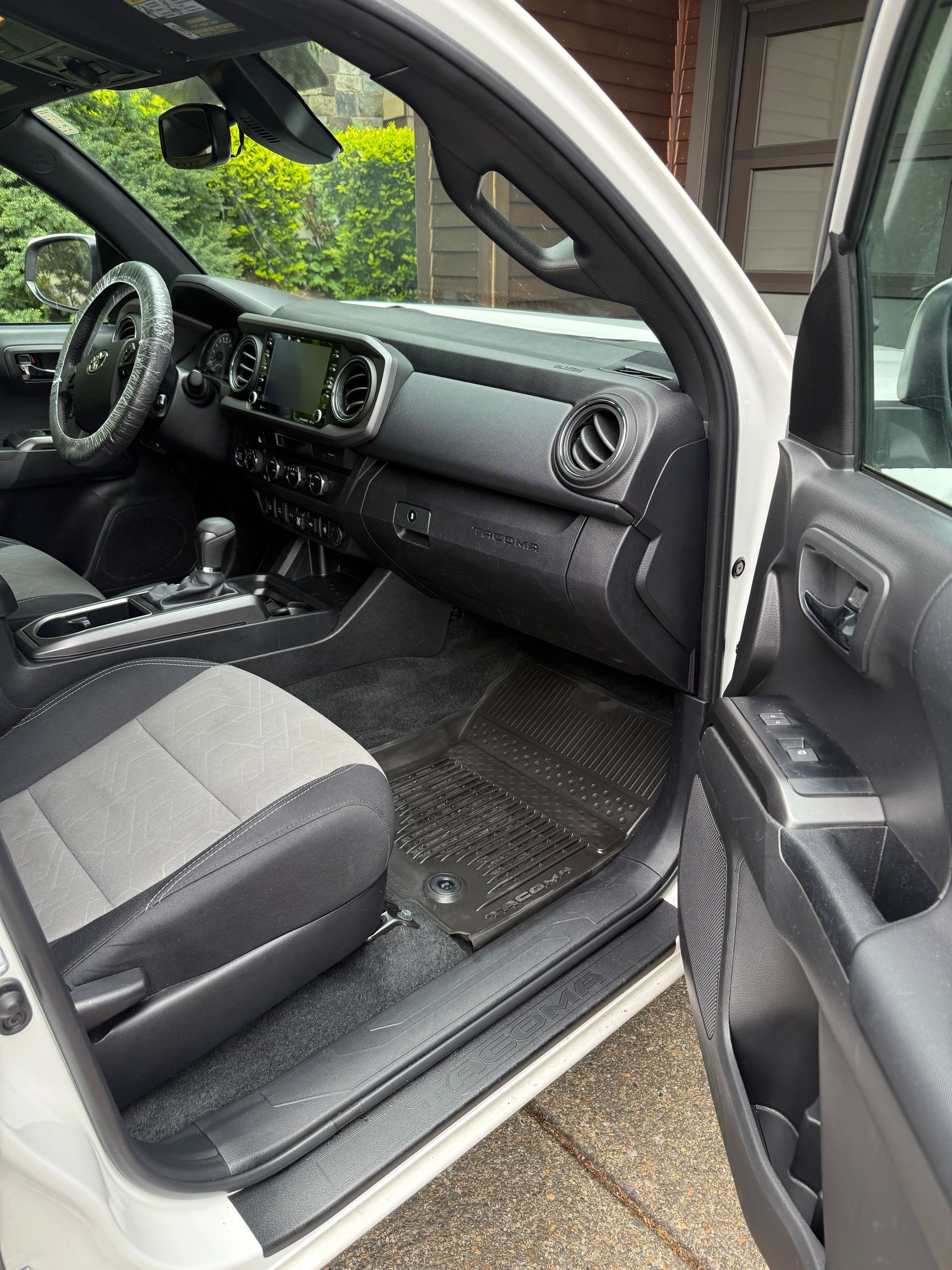 Car interior with open driver’s door, black dashboard and seats, viewed from outside