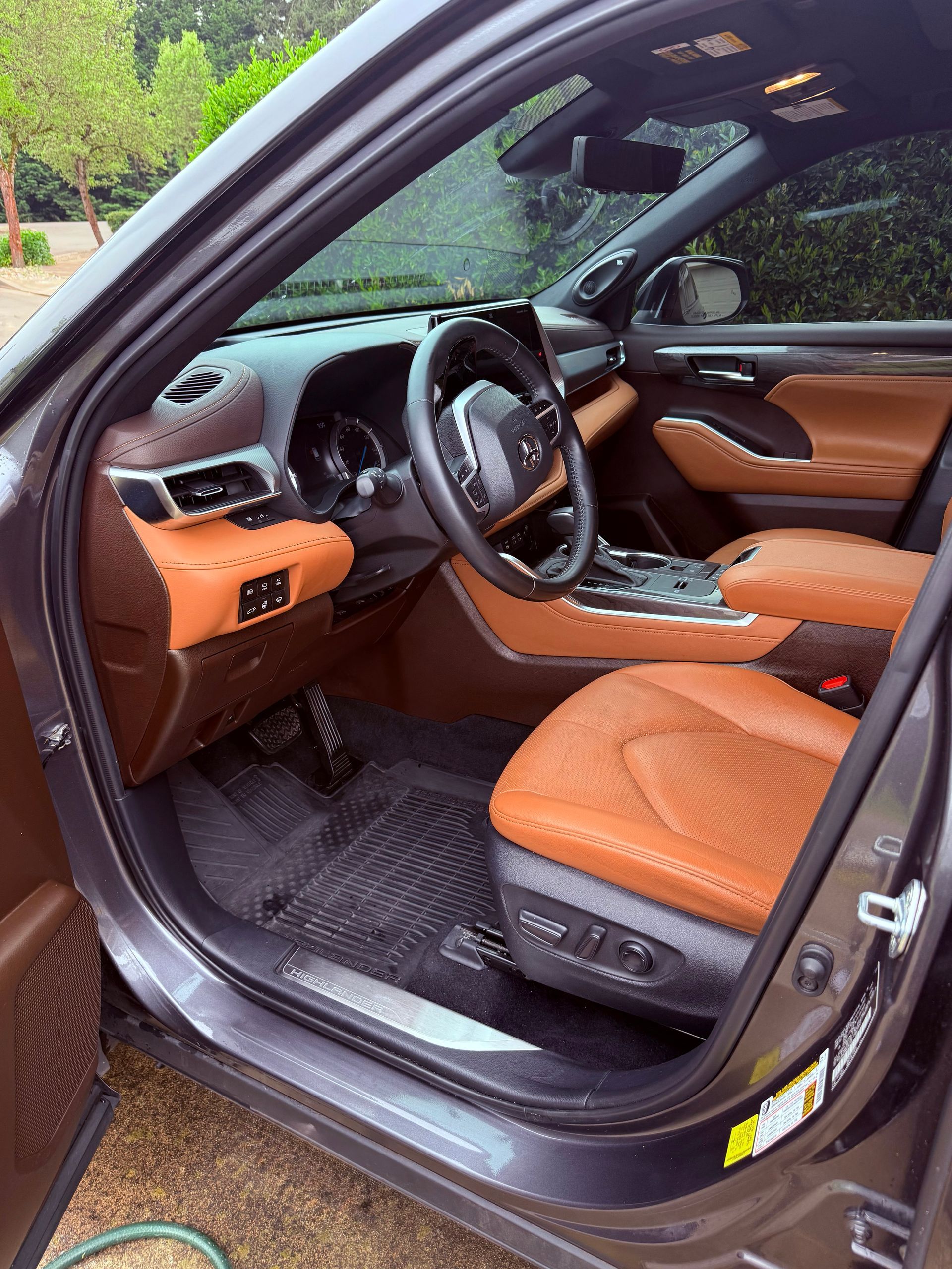 Open car door showing tan leather interior and black steering wheel in a parked vehicle